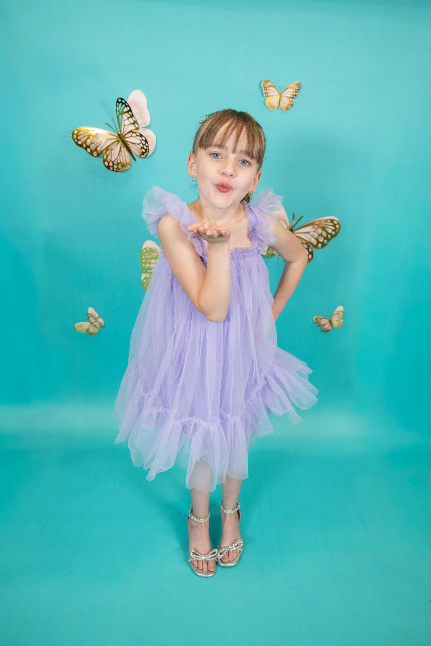 Dancing in a flowing purple dress with butterfly decorations on a bright aqua background.
