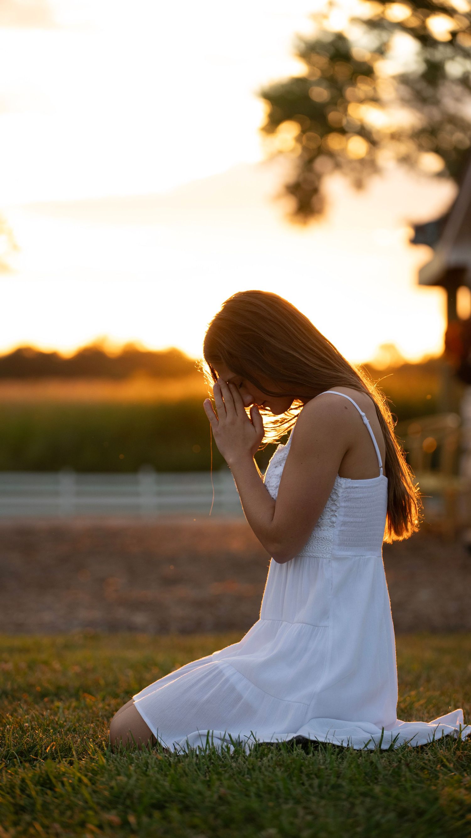 Artistic sunset portrait session featuring a flowing white dress on grassy ground.