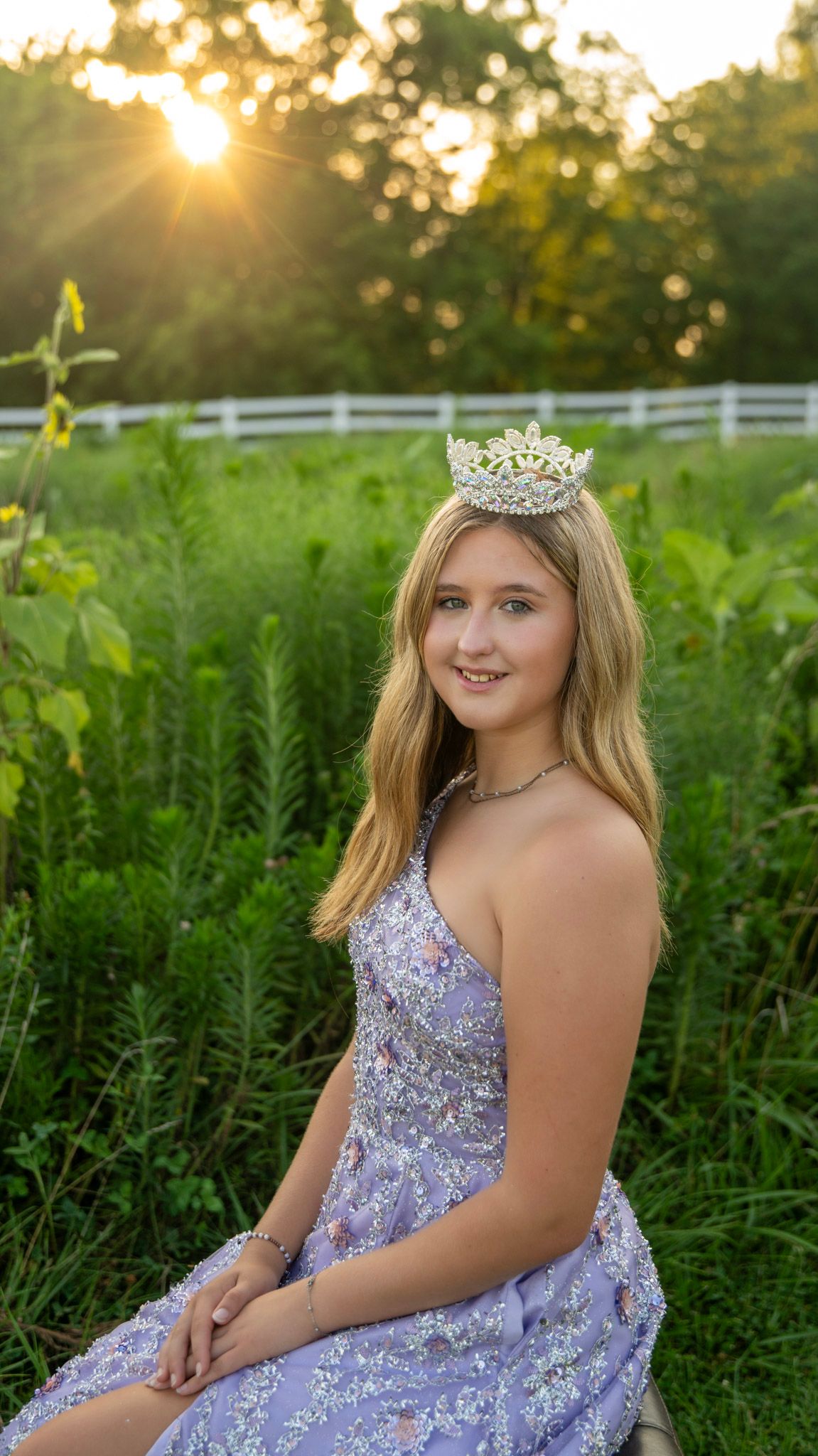 Golden hour portrait in a lavender ball gown with sunlit field backdrop.