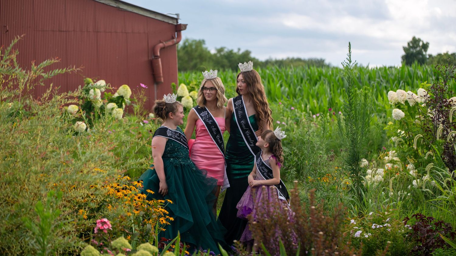 Group portrait captured in a flowering garden with rustic red barn backdrop.