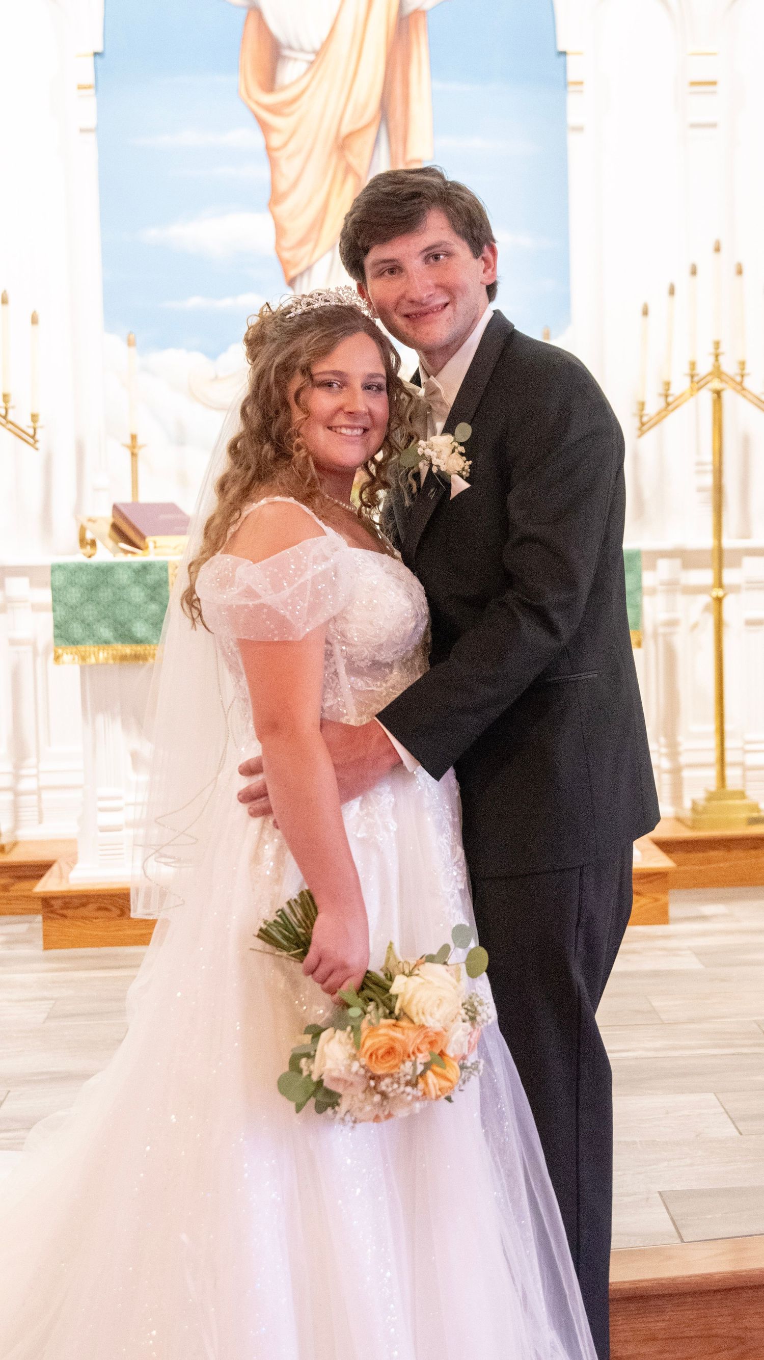 Newlyweds share a joyful moment in front of a church altar with elegant white and gold decor.