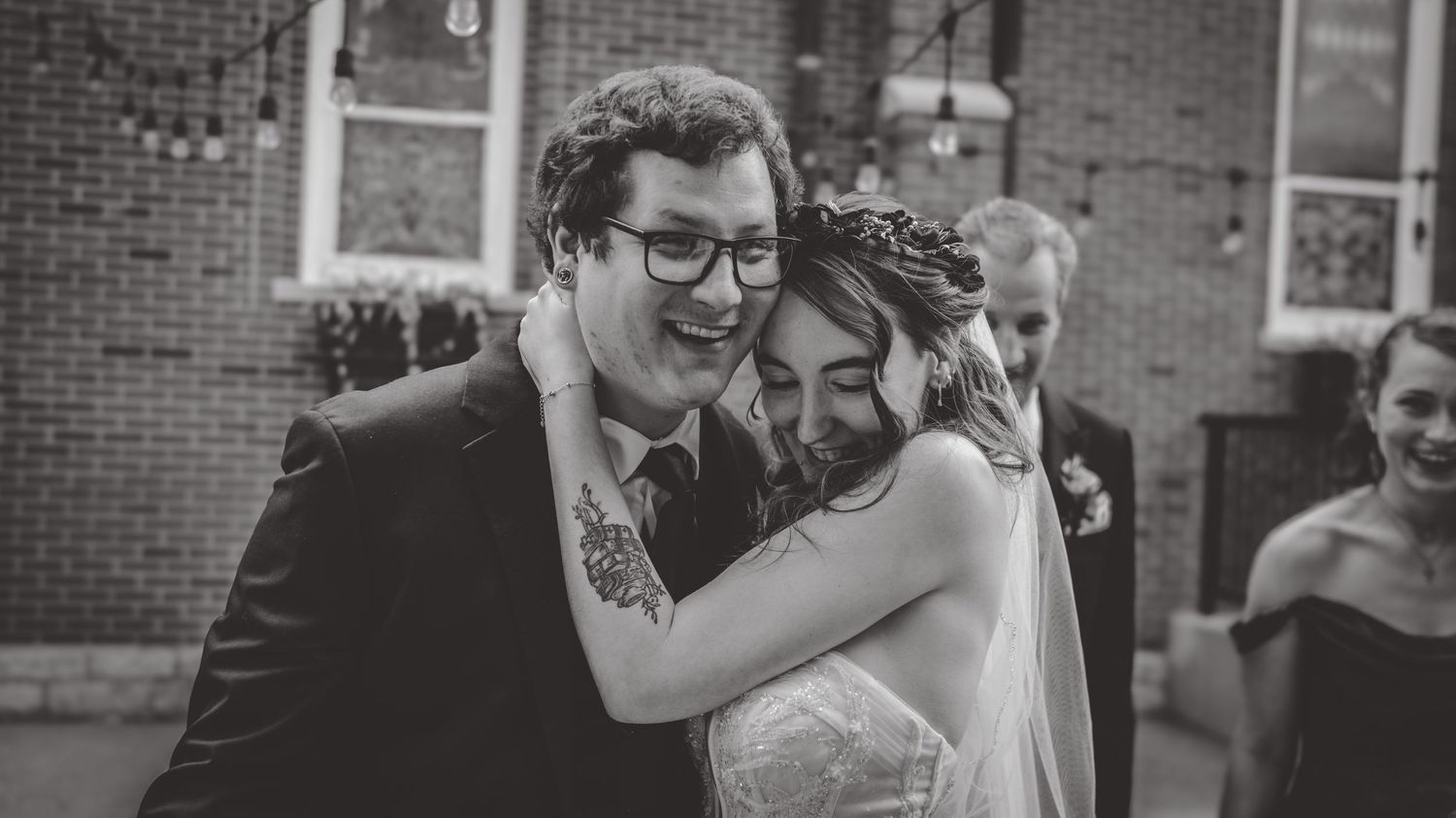 A tender black and white wedding moment captured against a brick building.