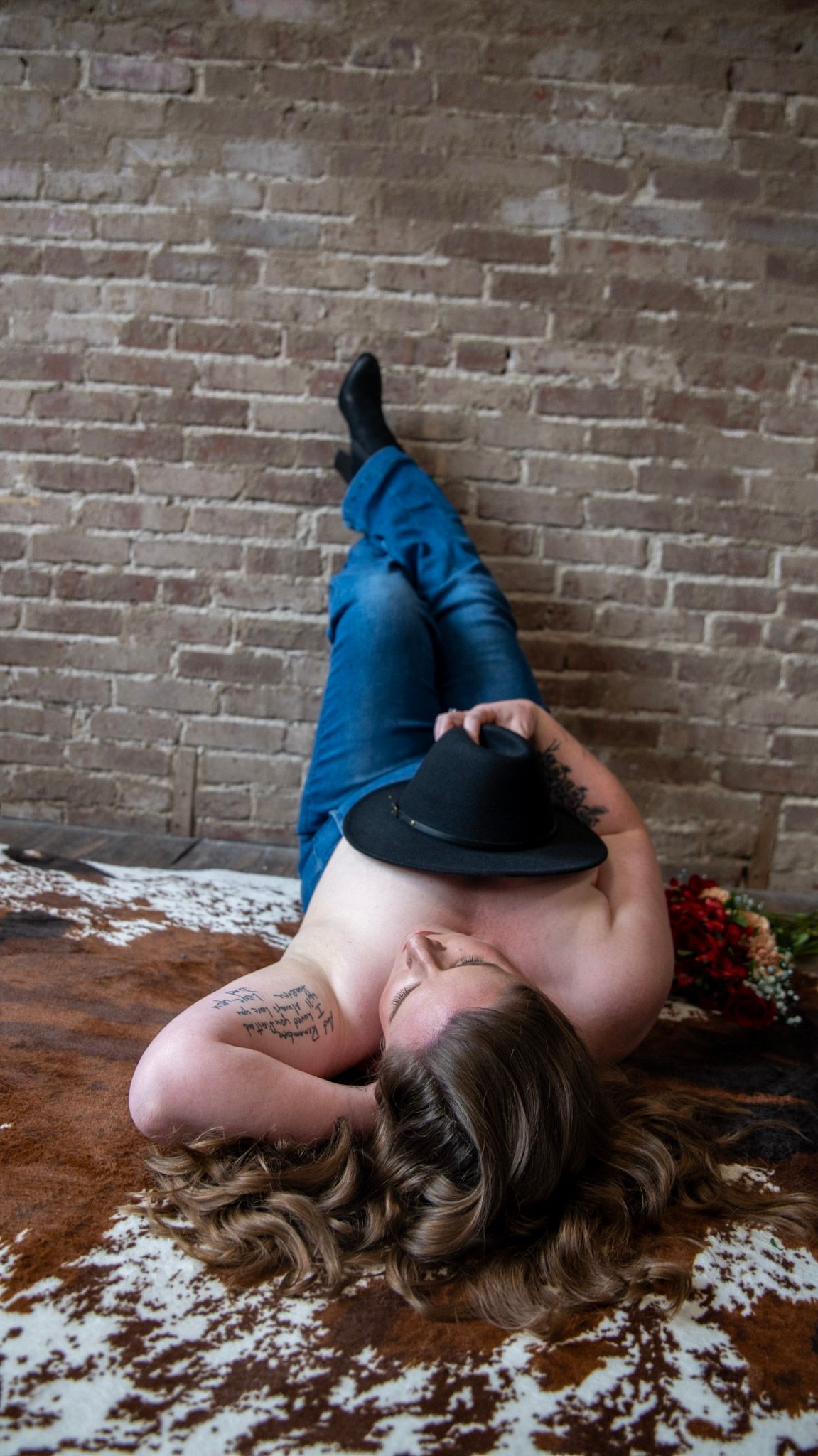Artistic boudoir sequence showing person in denim with red flowers against rustic backdrop.