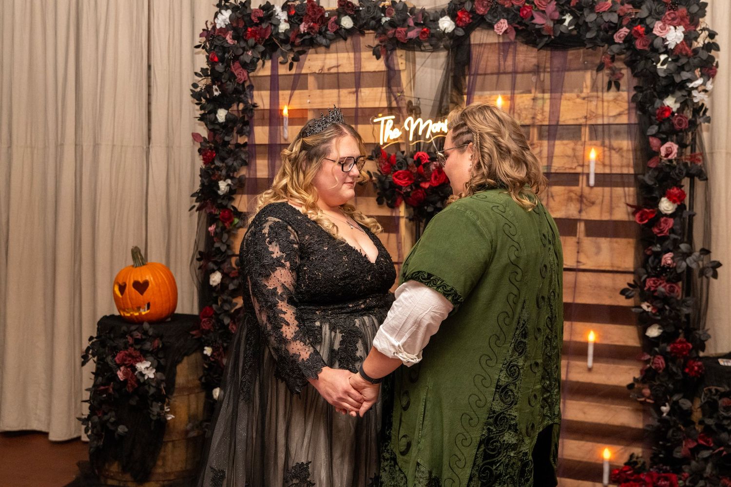 Gothic wedding reception decor featuring red roses and wooden pallet backdrop.