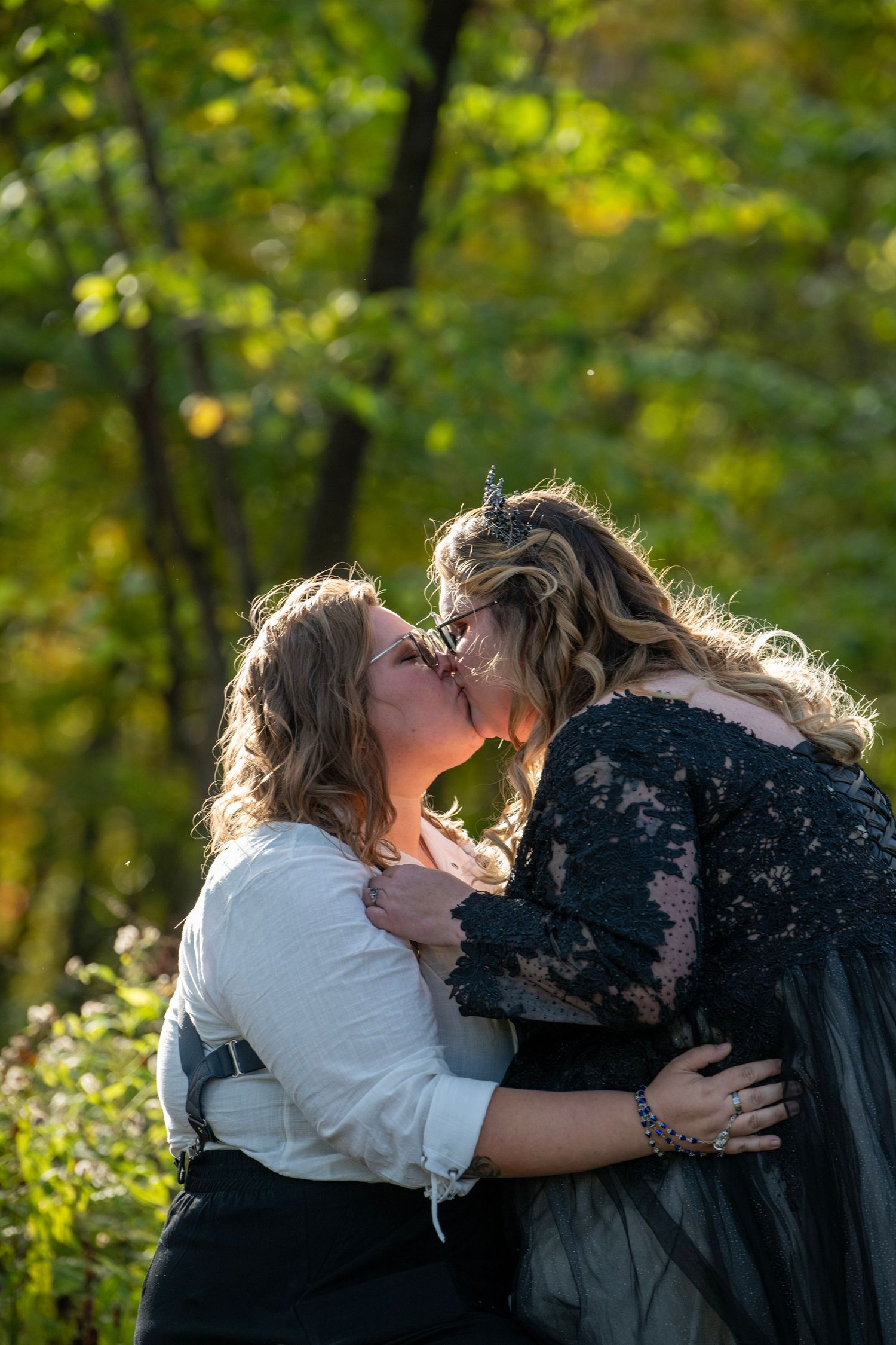 Romantic couple sharing an intimate moment in a sunlit forest setting.