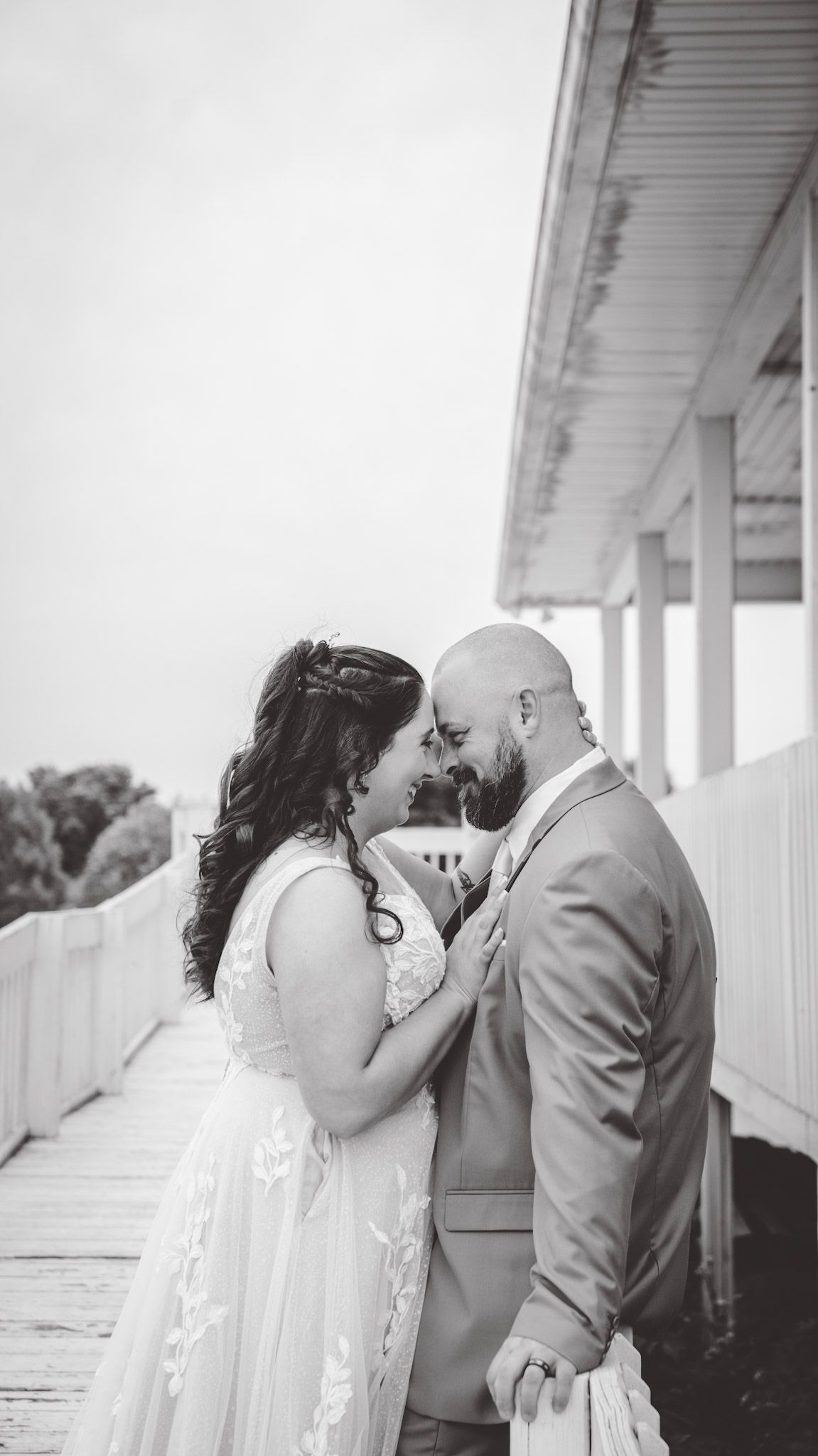 Black and white wedding photos showing tender moments between newlyweds on a white porch.