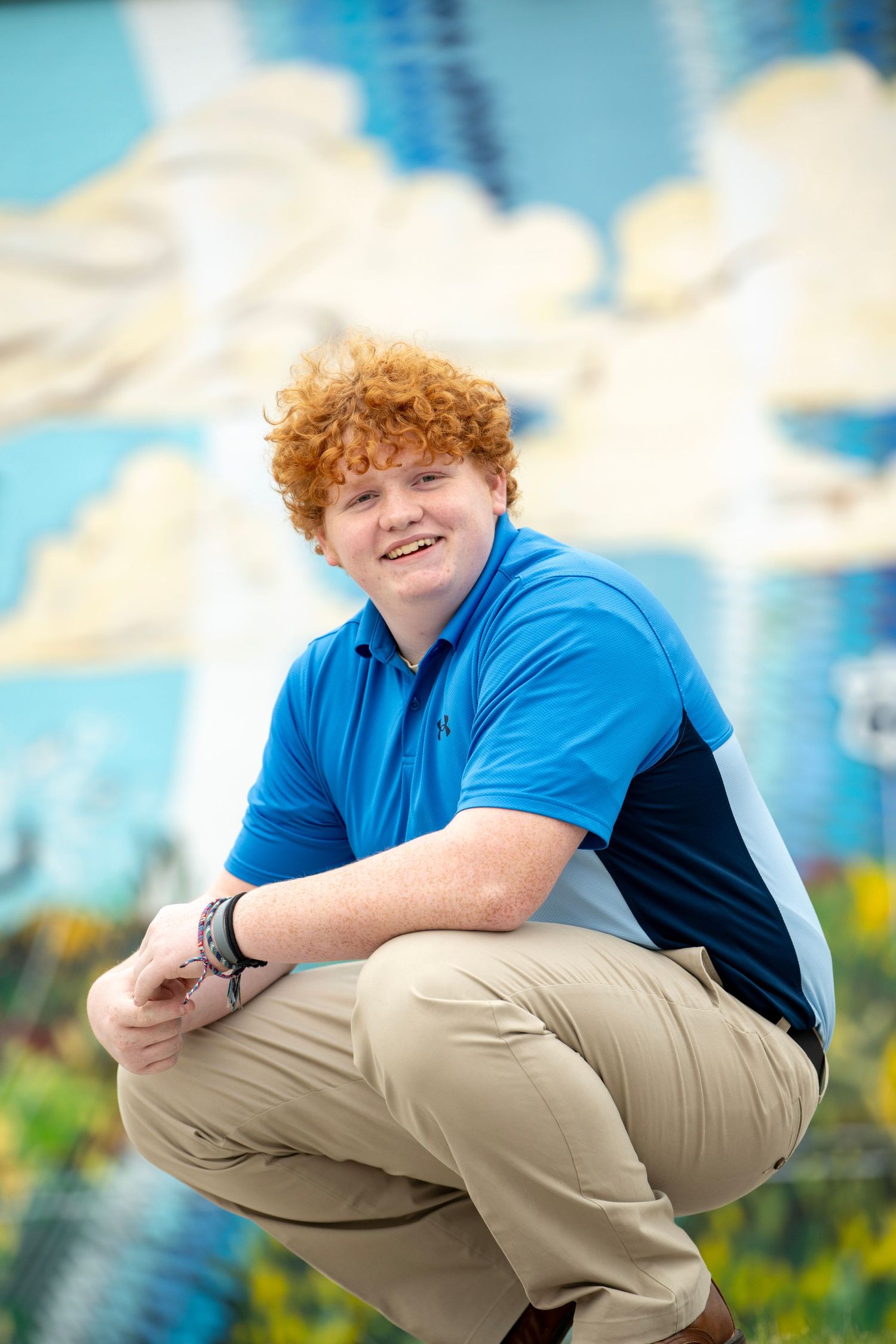 Series of crouching poses in blue polo shirt against artistic backdrop.