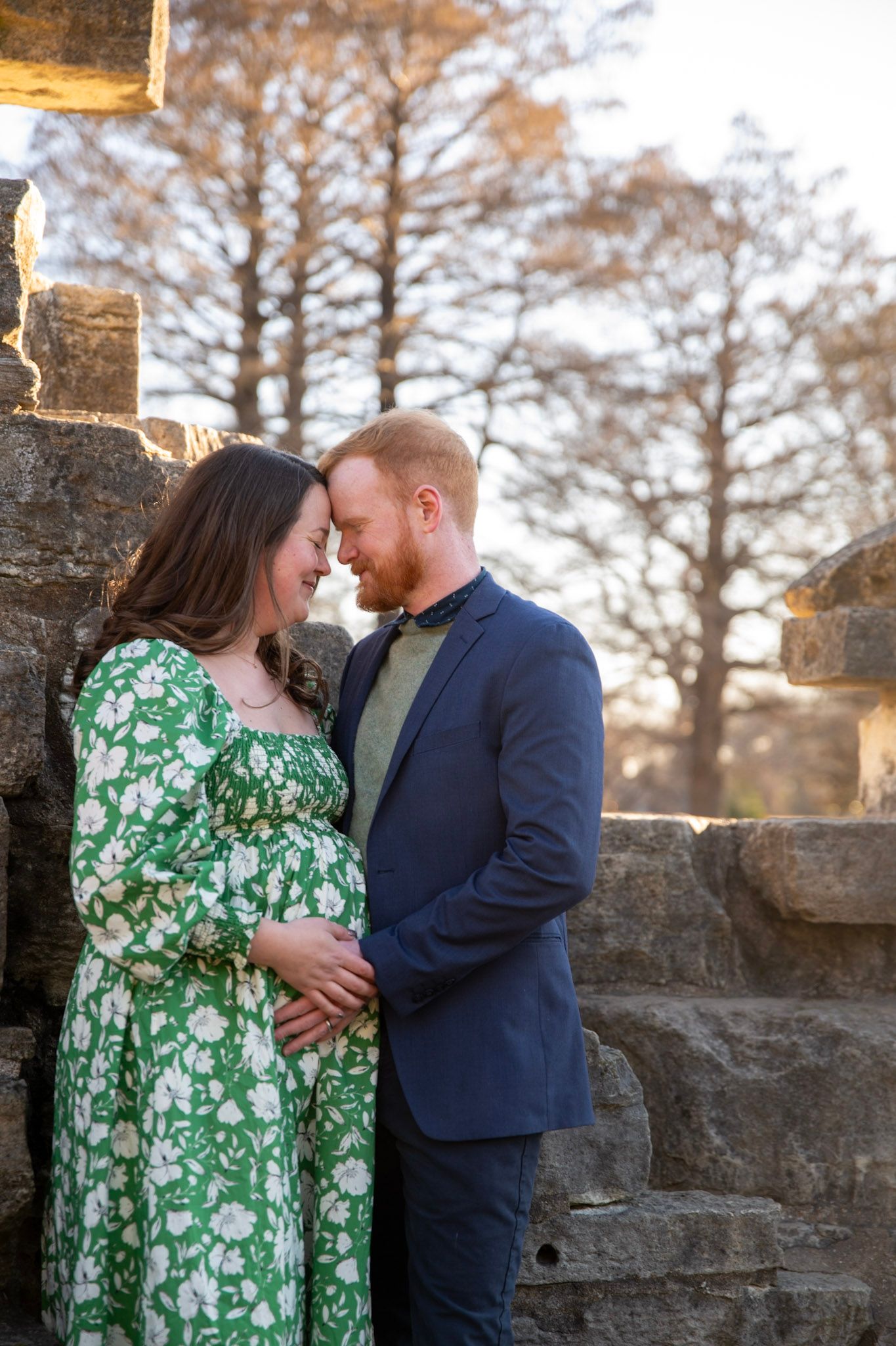 Couple sharing intimate moment against stone wall backdrop during autumn outdoor photoshoot.