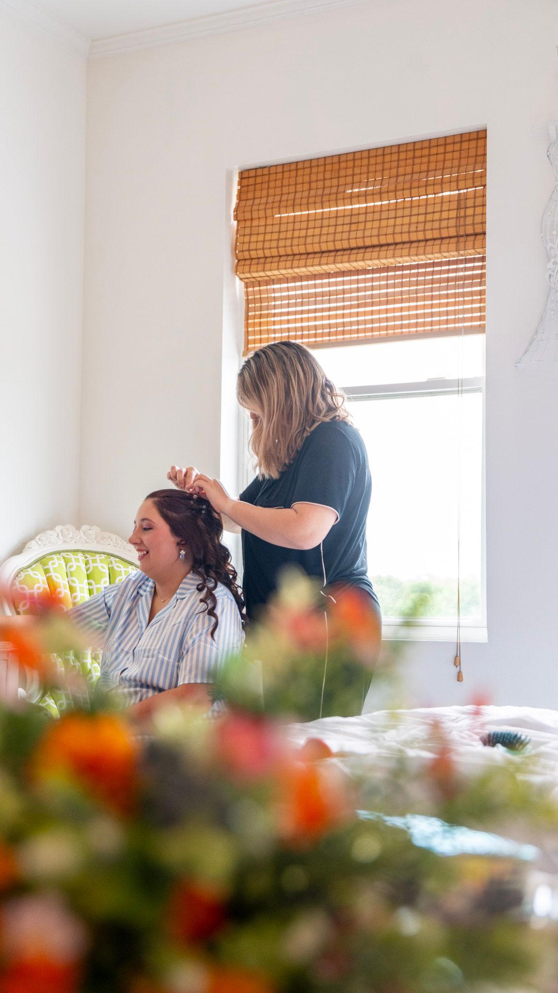 Hair and makeup preparation scene with orange flowers in foreground.