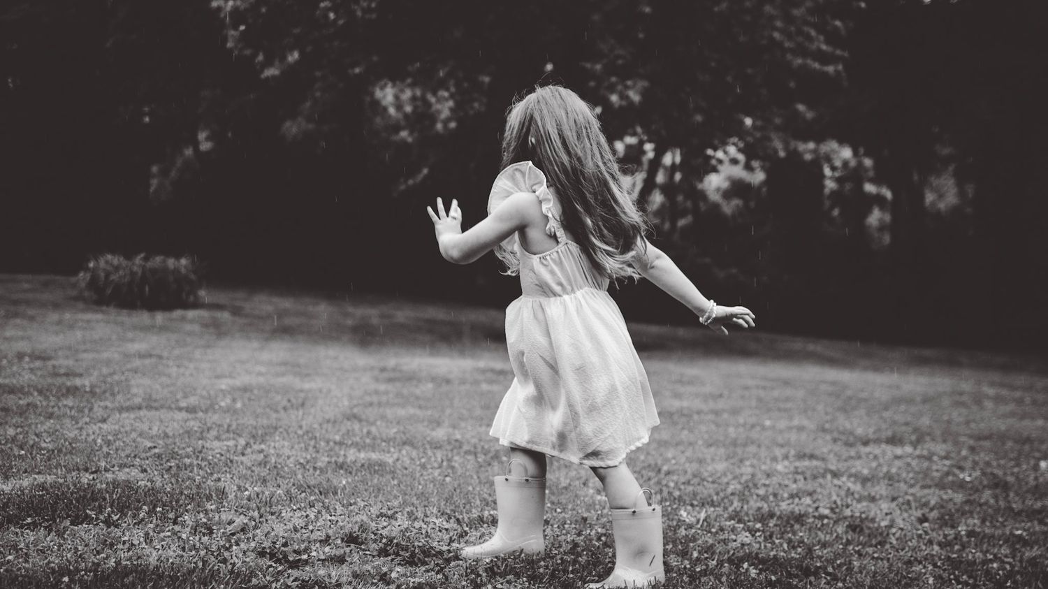 Black and white panoramic shot of children playing outdoors on grass.