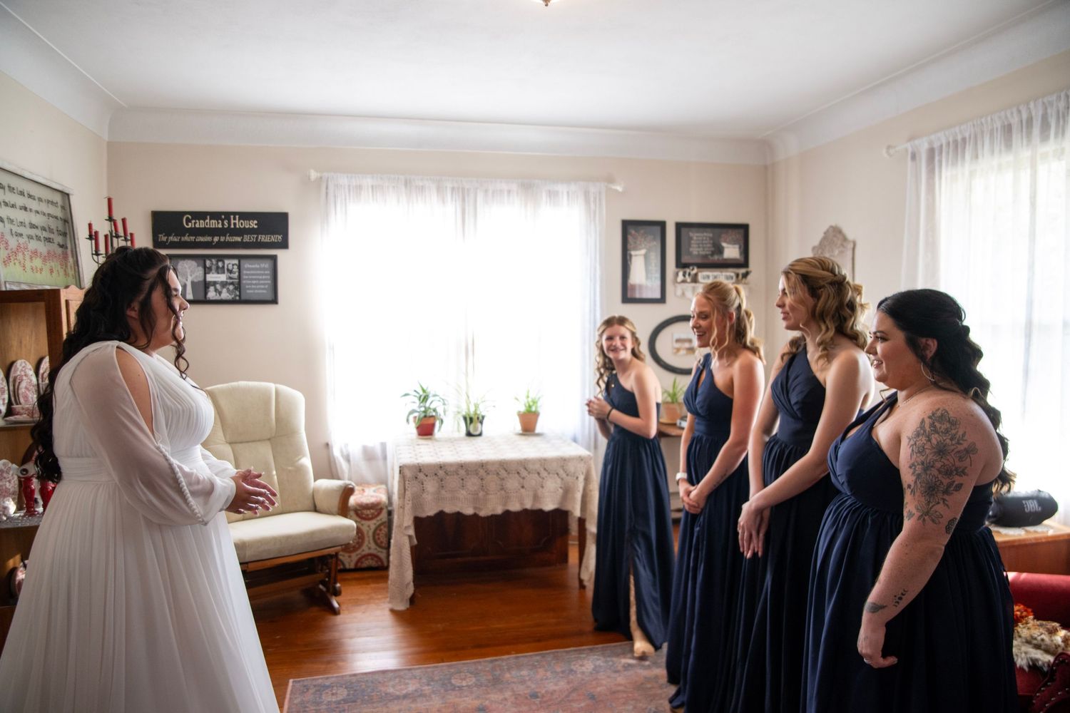 Wedding preparation scene with bridesmaids in navy dresses in sunlit room.