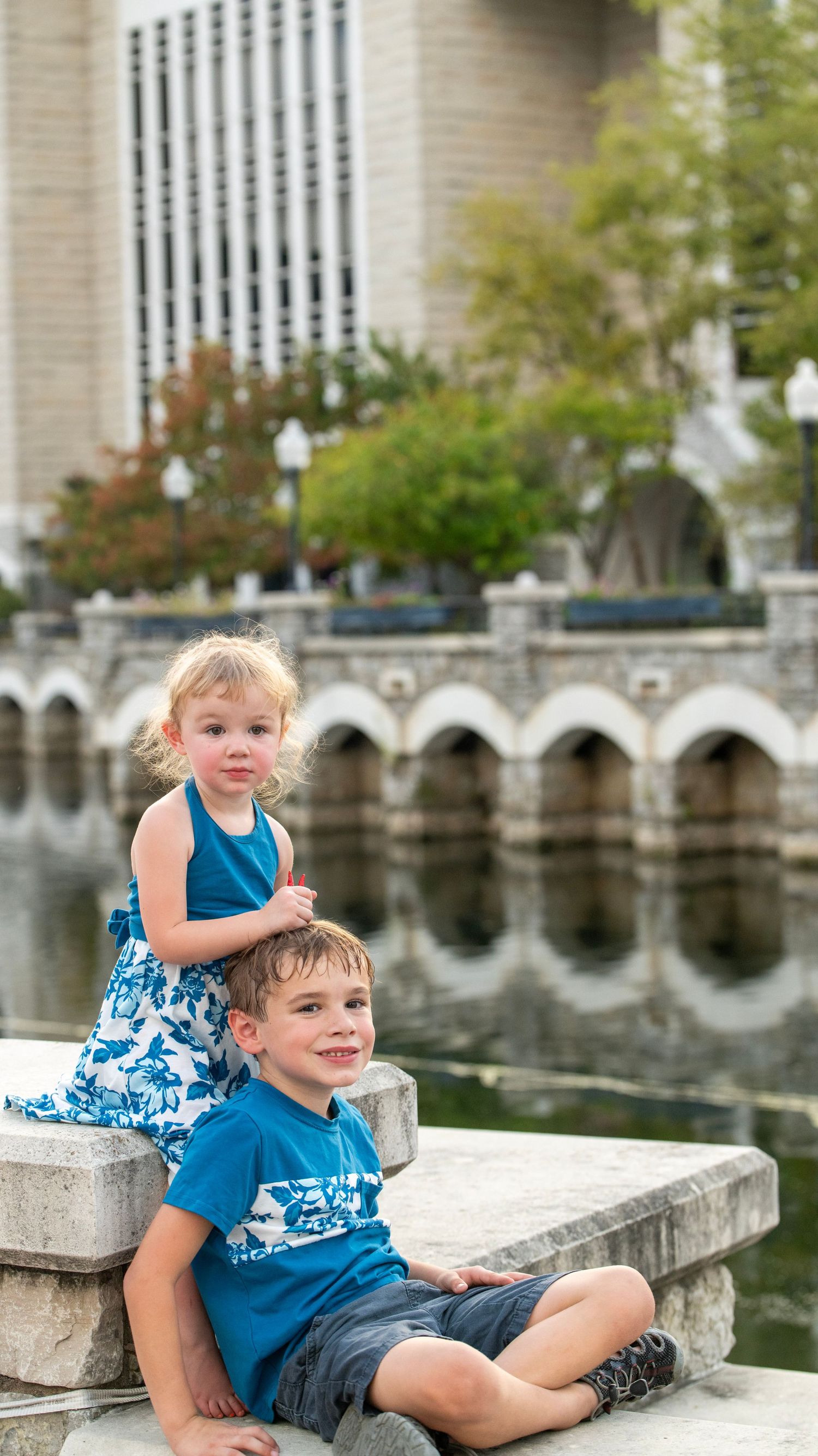 Candid family moments captured by stone architecture and reflecting pool.