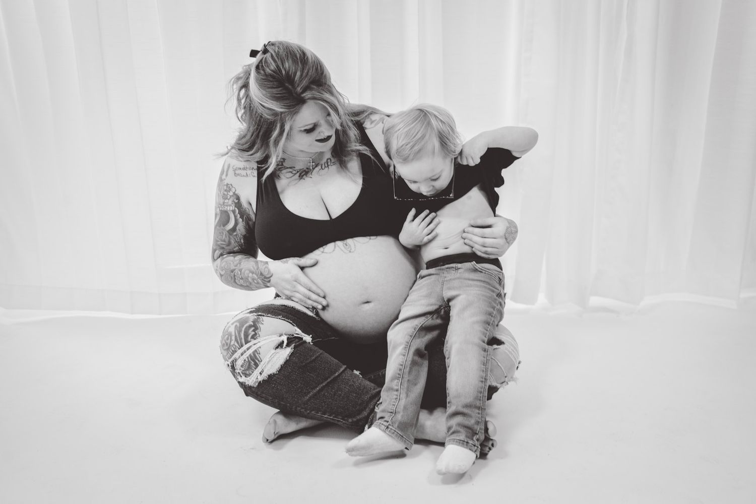 Intimate maternity portraits in white studio setting with soft natural lighting.