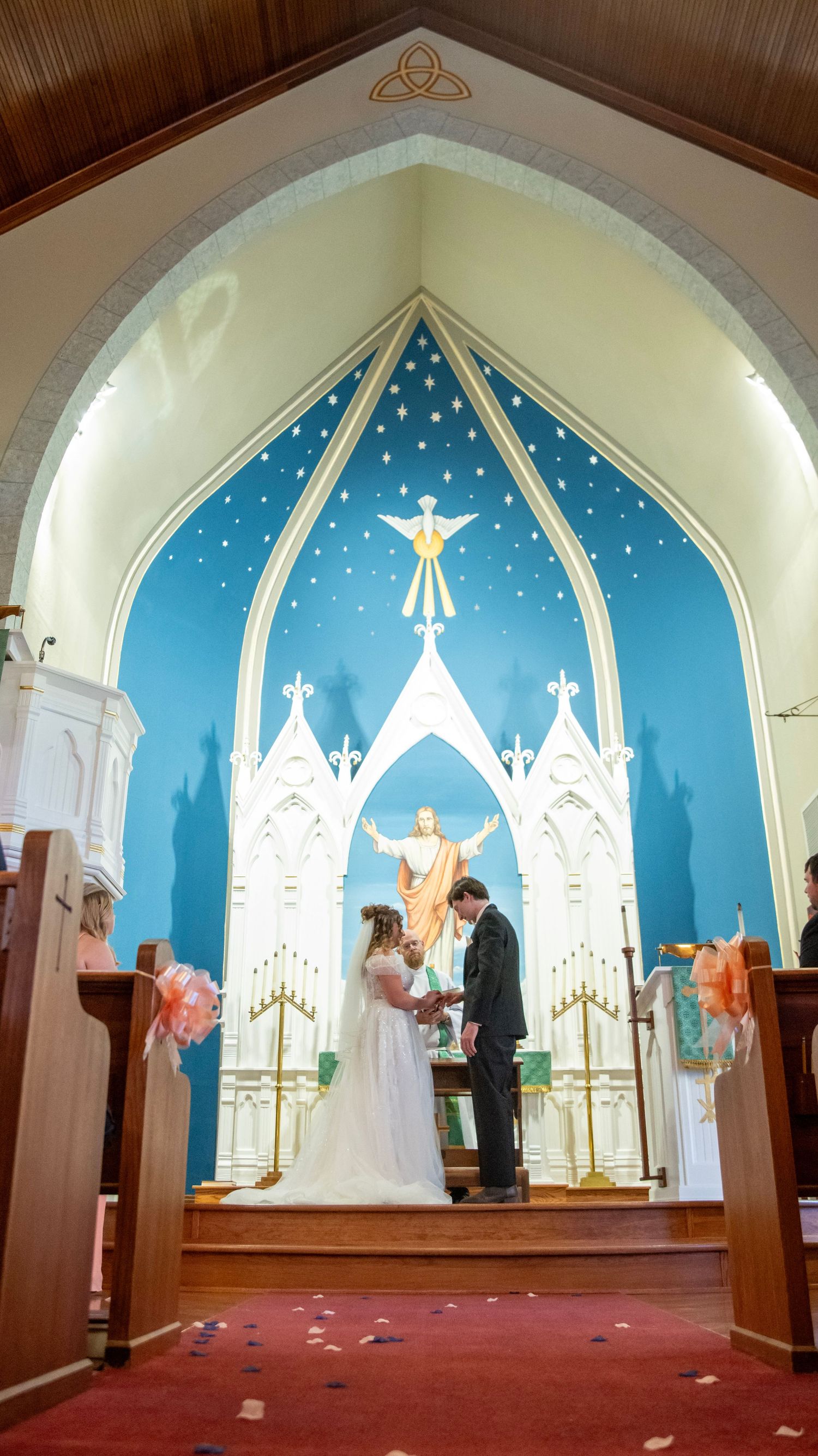 Wedding ceremony in a church with distinctive blue altar backdrop featuring white castle-like designs.