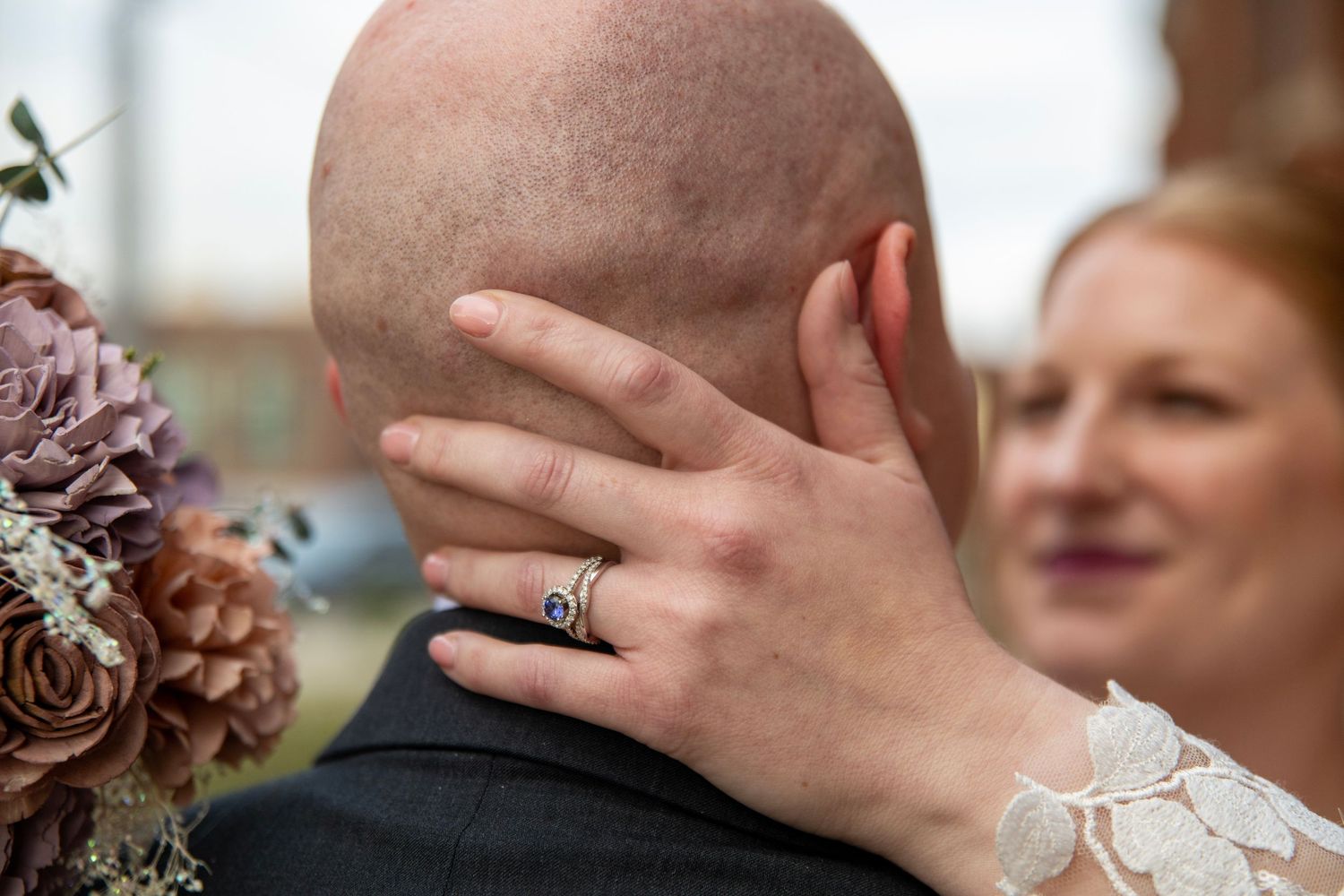 Wedding couple's hands with rings showcased against floral decorations.