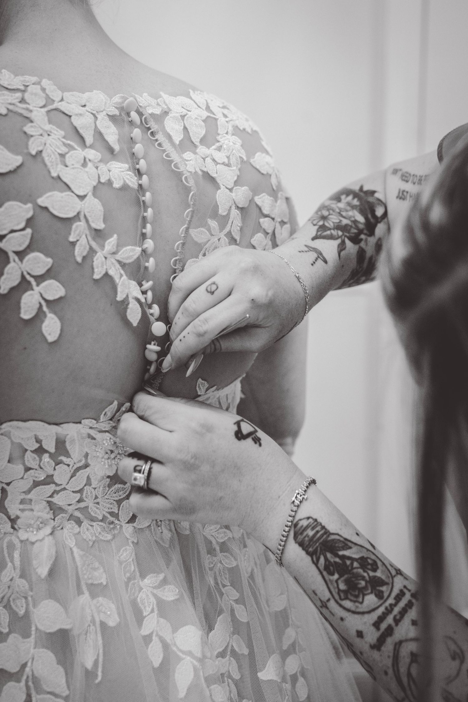 Close-up of intricate lace details being adjusted on wedding dress.