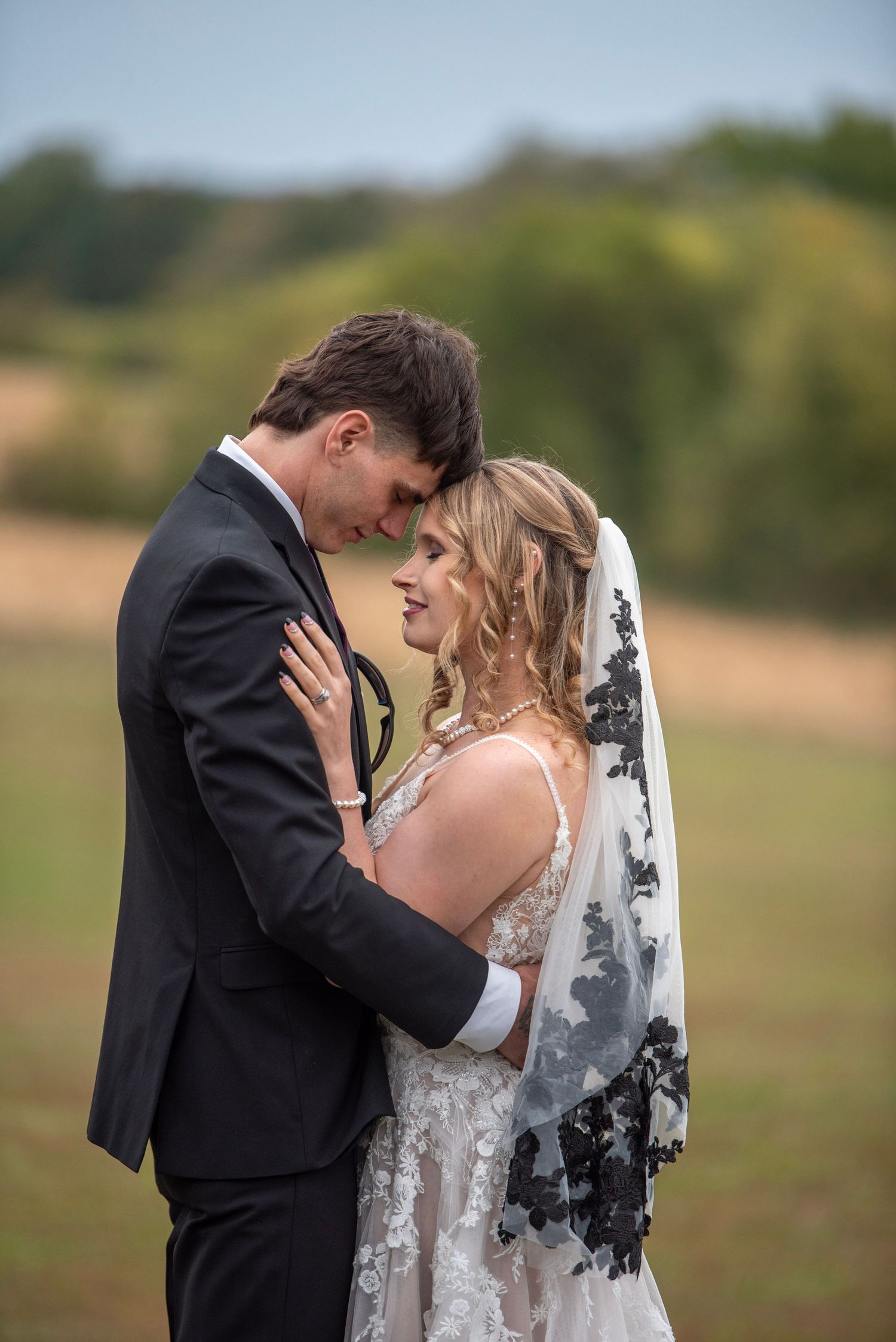 Candid wedding photo showing tender interaction between newlyweds in an outdoor setting.
