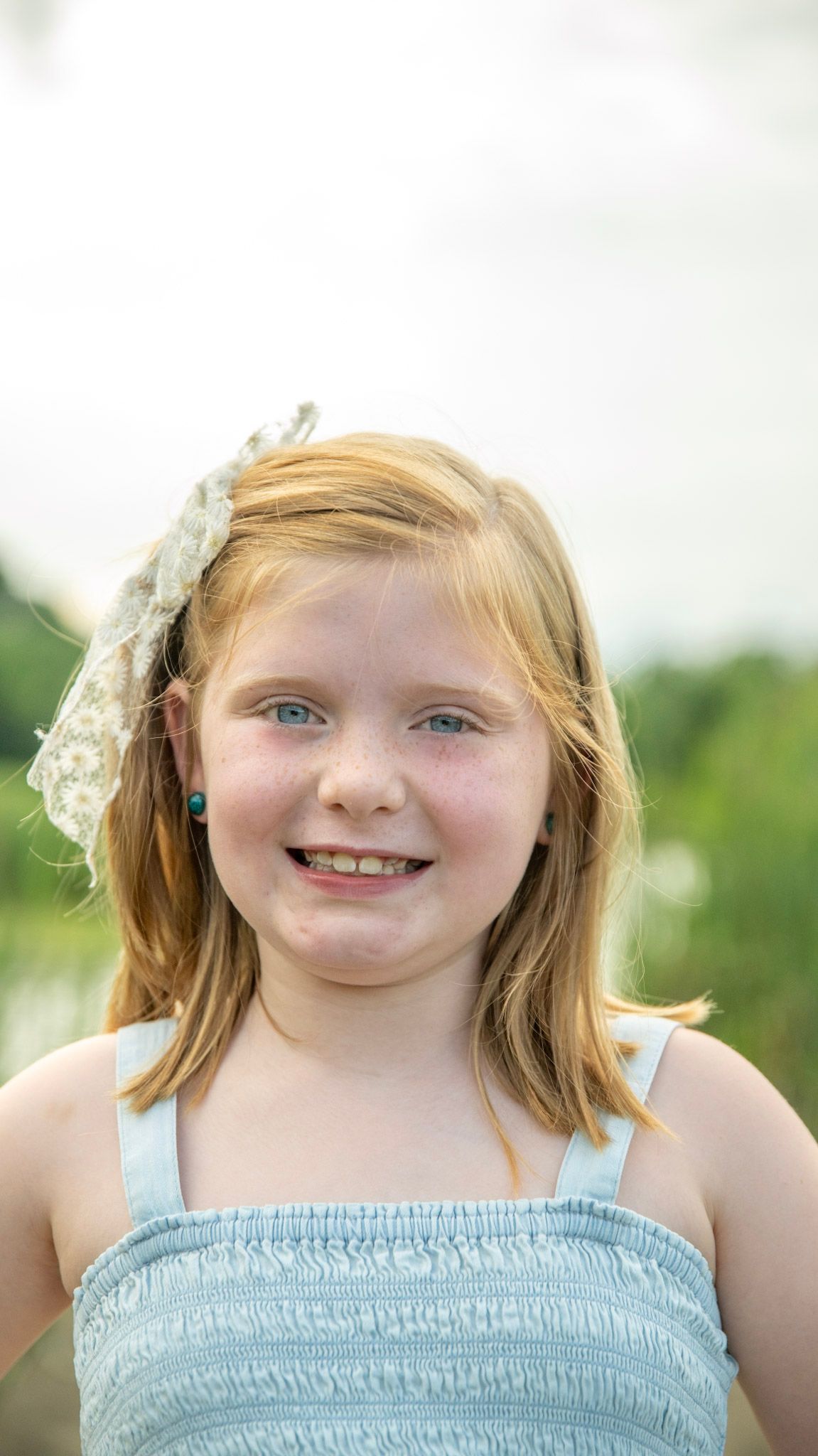 Summer portrait in light blue dress against natural background.