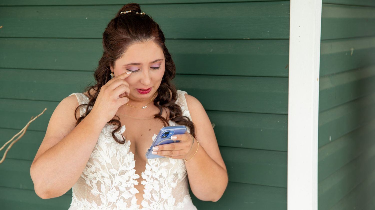 Emotional reactions during wedding first look against green exterior.