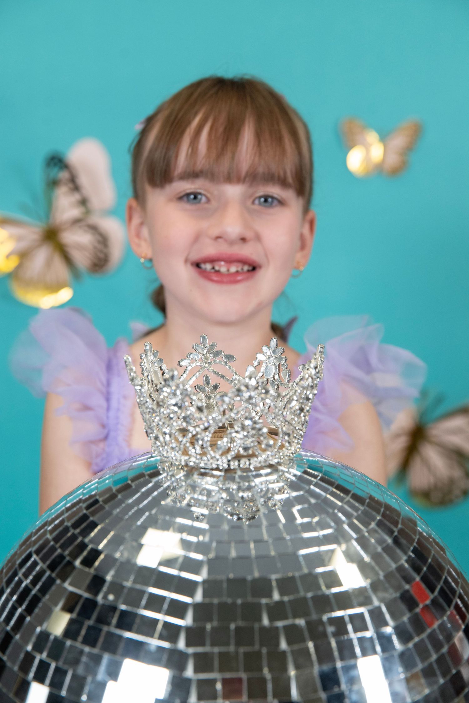 A shiny disco ball reflects light against a turquoise background creating a festive party atmosphere.