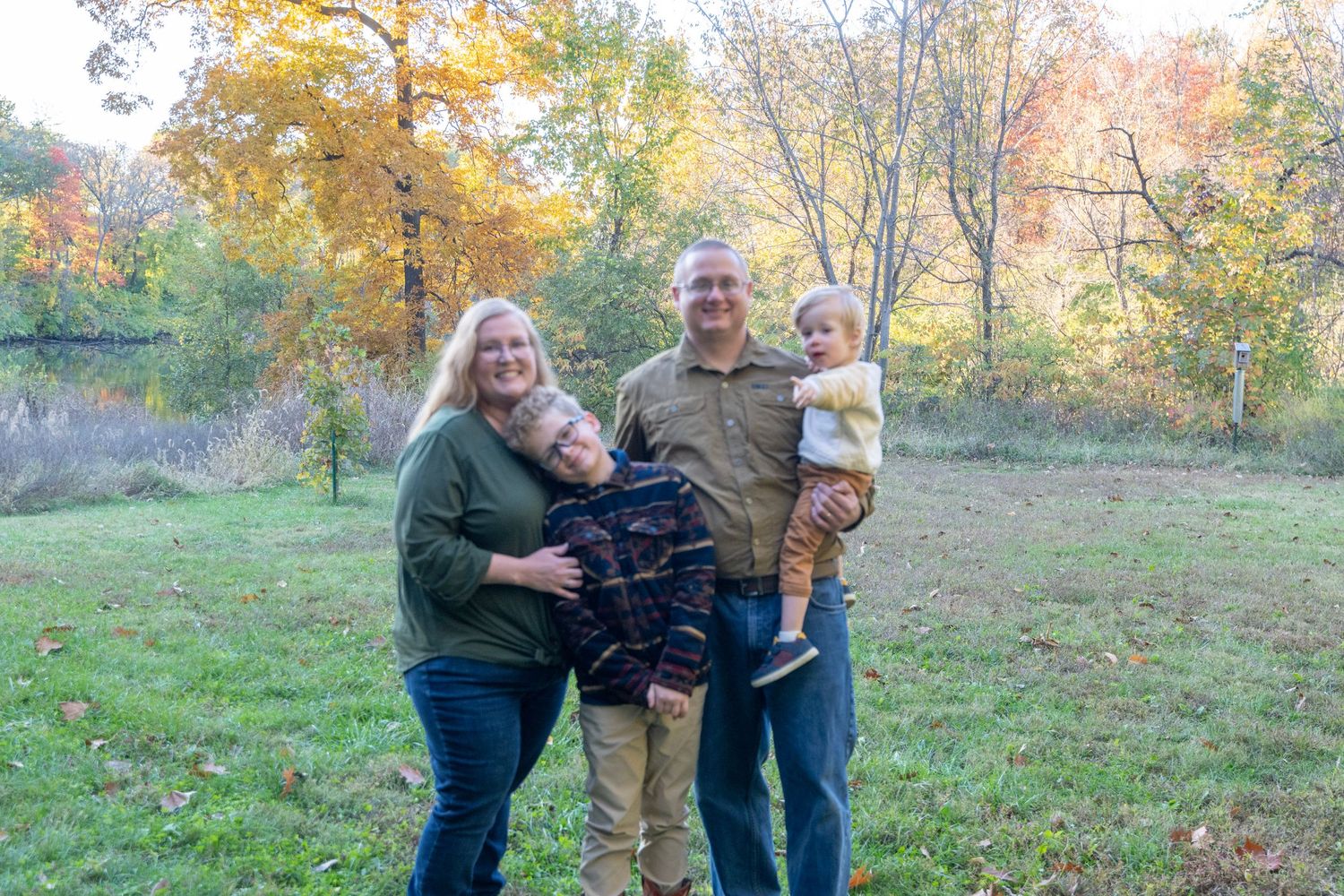 Group poses together in a natural outdoor setting with fall foliage visible in the background.