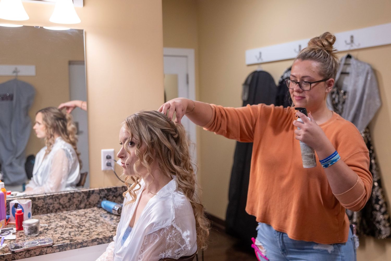 Wedding preparations underway as makeup and hair styling takes place in a beige-toned room.