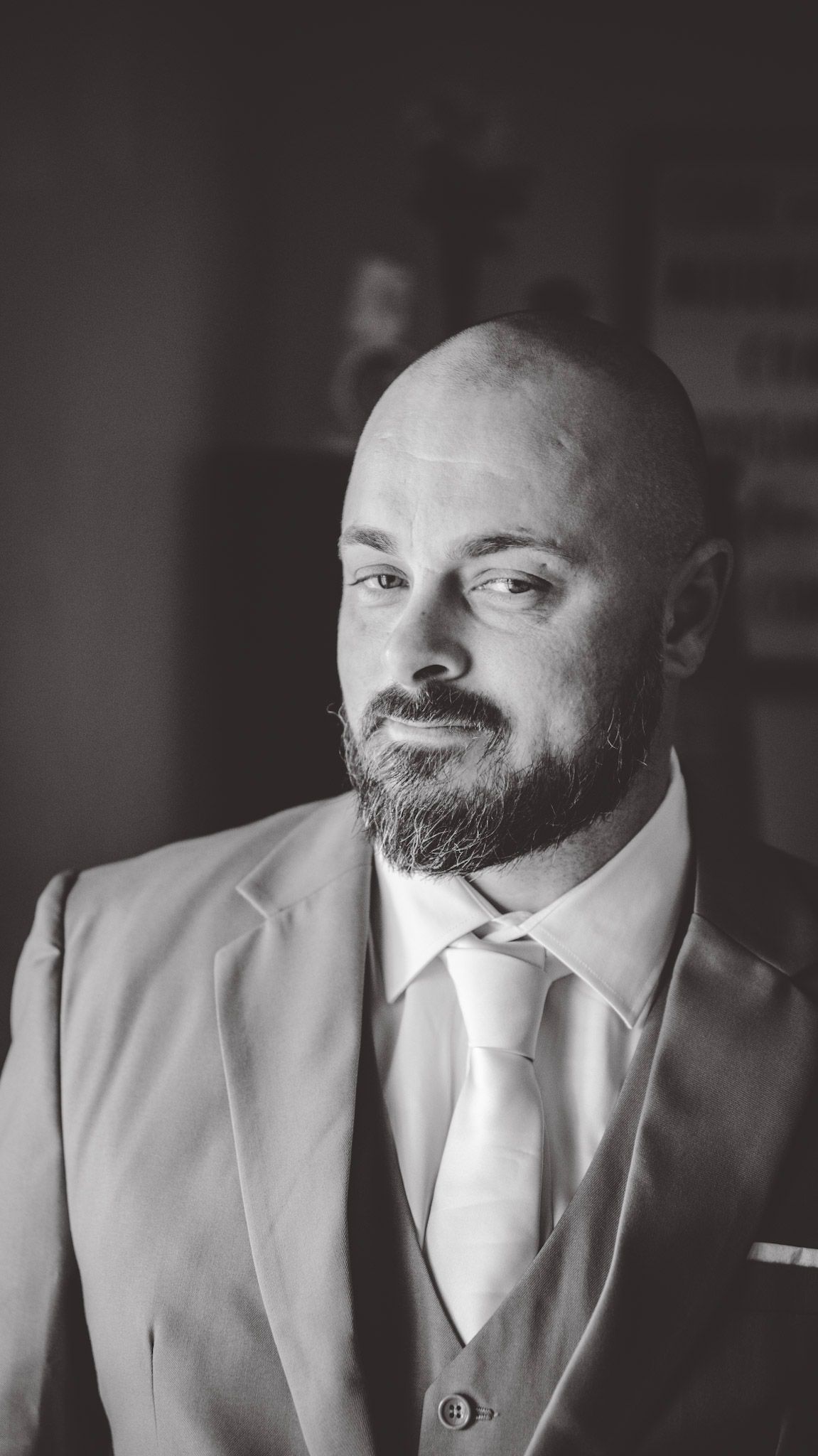 Black and white portraits of a bearded groom in formal attire smiling at the camera.