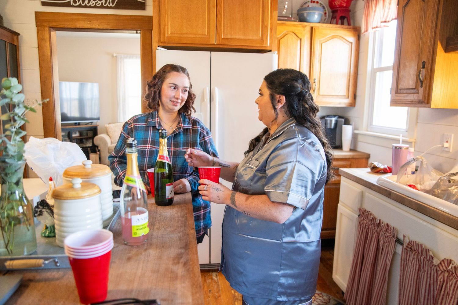 Two people chatting and laughing in casual kitchen setting during wedding preparations.