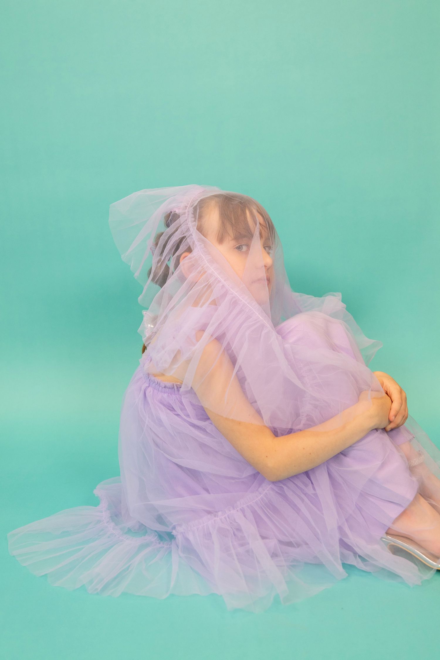 A dreamy portrait with flowing purple tulle fabric against a mint green background.