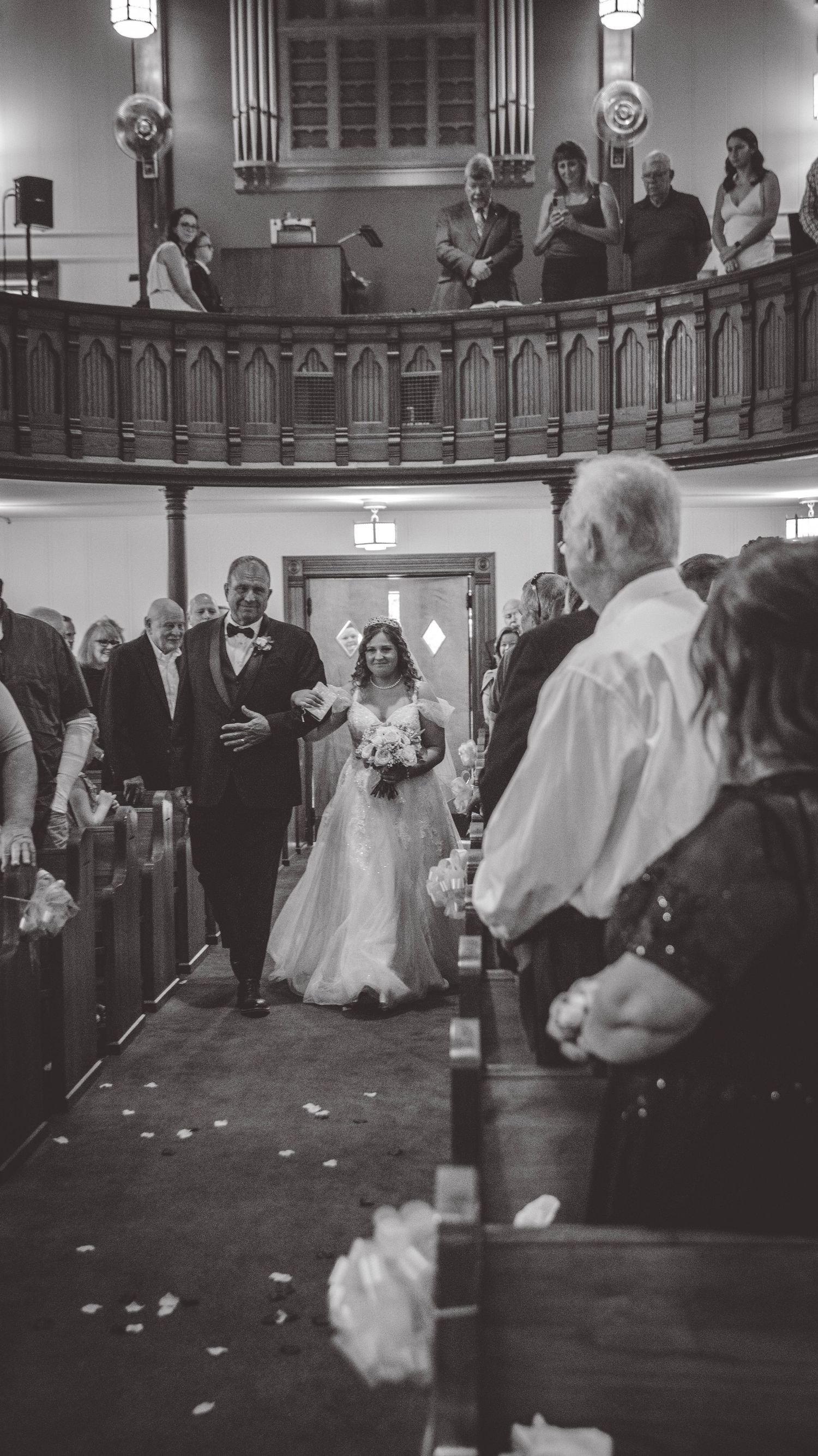 A sequence of wedding ceremony moments captured in black and white showing movement across a church aisle.