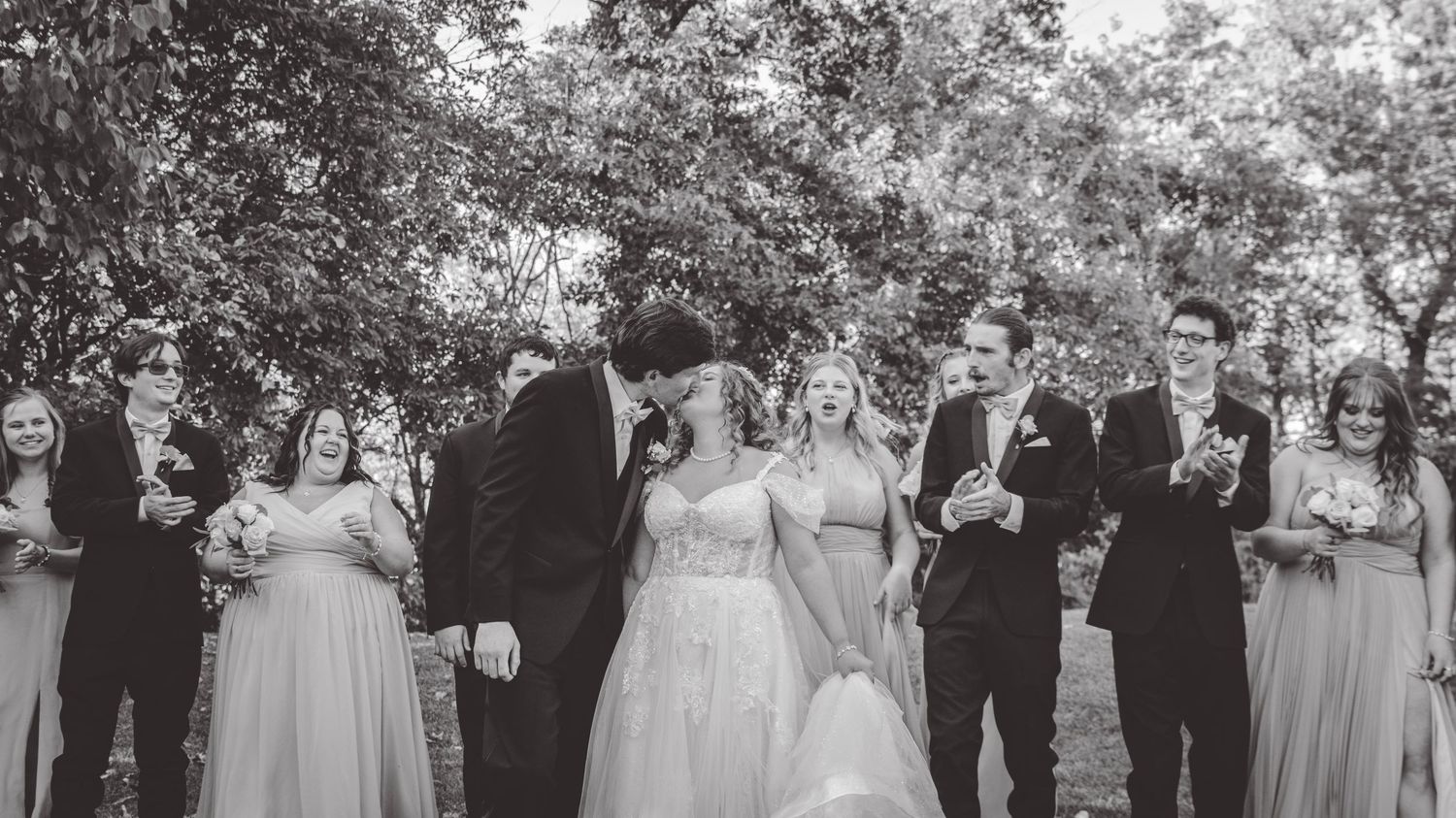 Black and white photo of wedding party lined up outdoors for formal portraits.