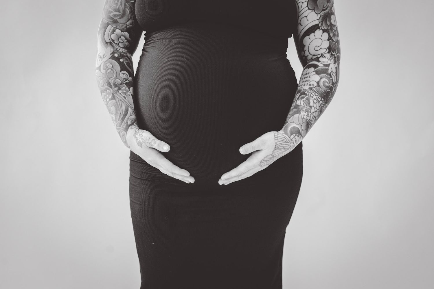 Artistic black and white photos focusing on hands cradling pregnant belly.