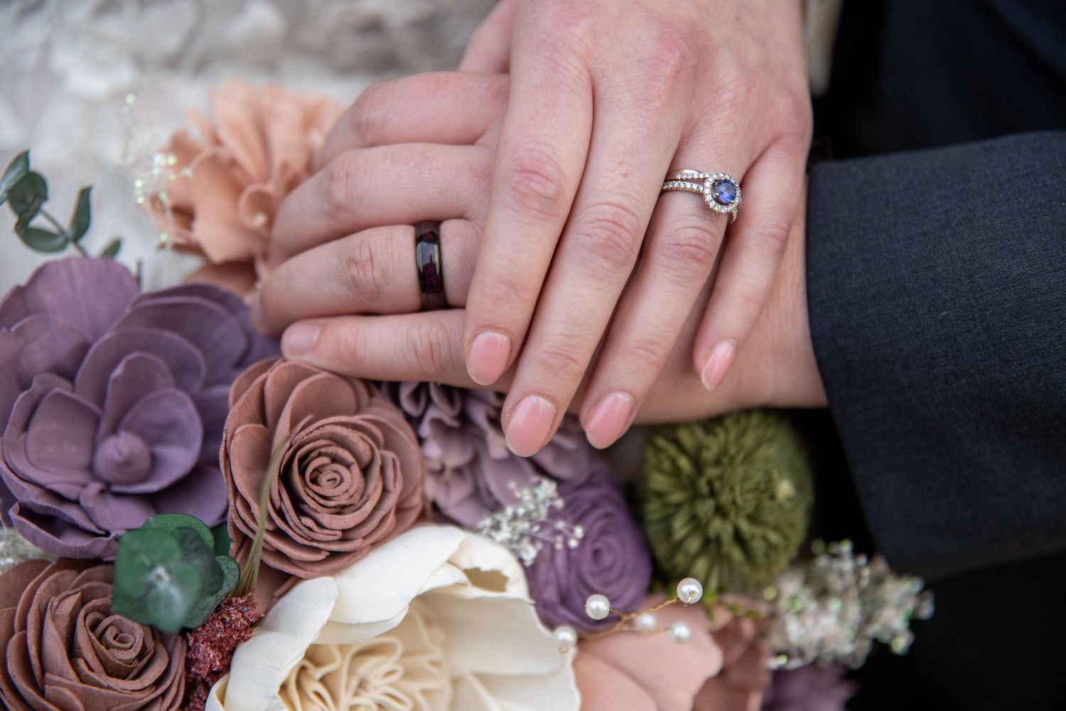 Wedding rings displayed with purple and blush roses in the background.
