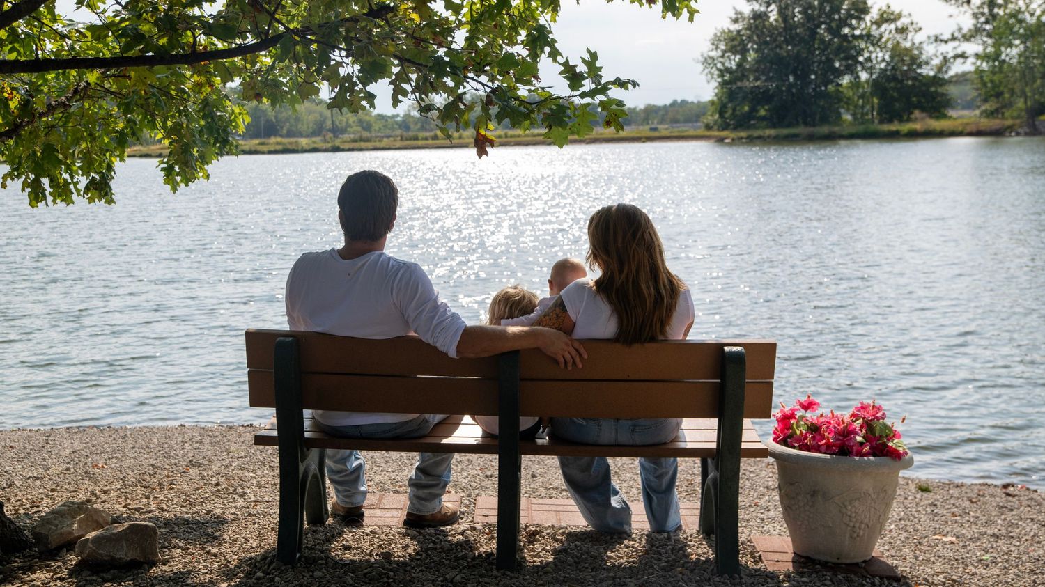 Scenic lakeside view with a wooden gazebo and trees in the background.