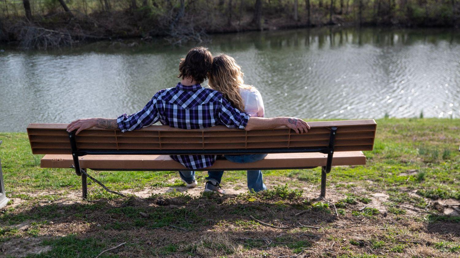 Wide panoramic view of a park with a bench near a lake or pond.