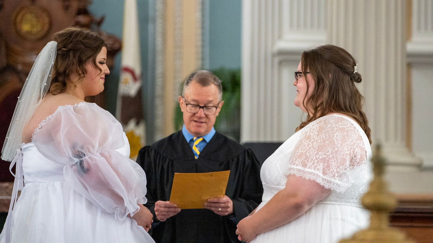 Wedding ceremony in a grand courthouse with classical architecture and decorative details.