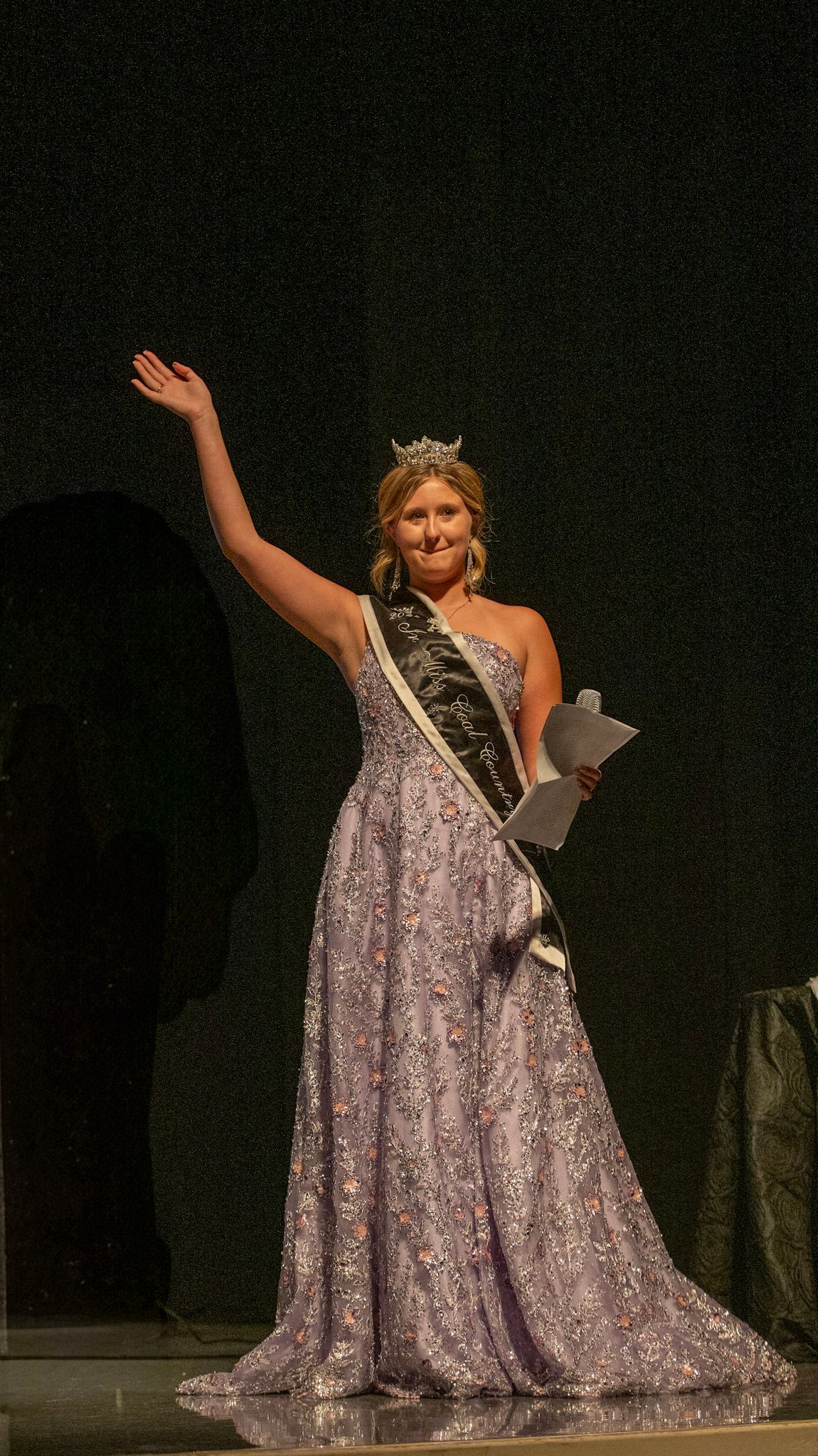 A contestant in a flowing lavender gown poses gracefully during a pageant performance.