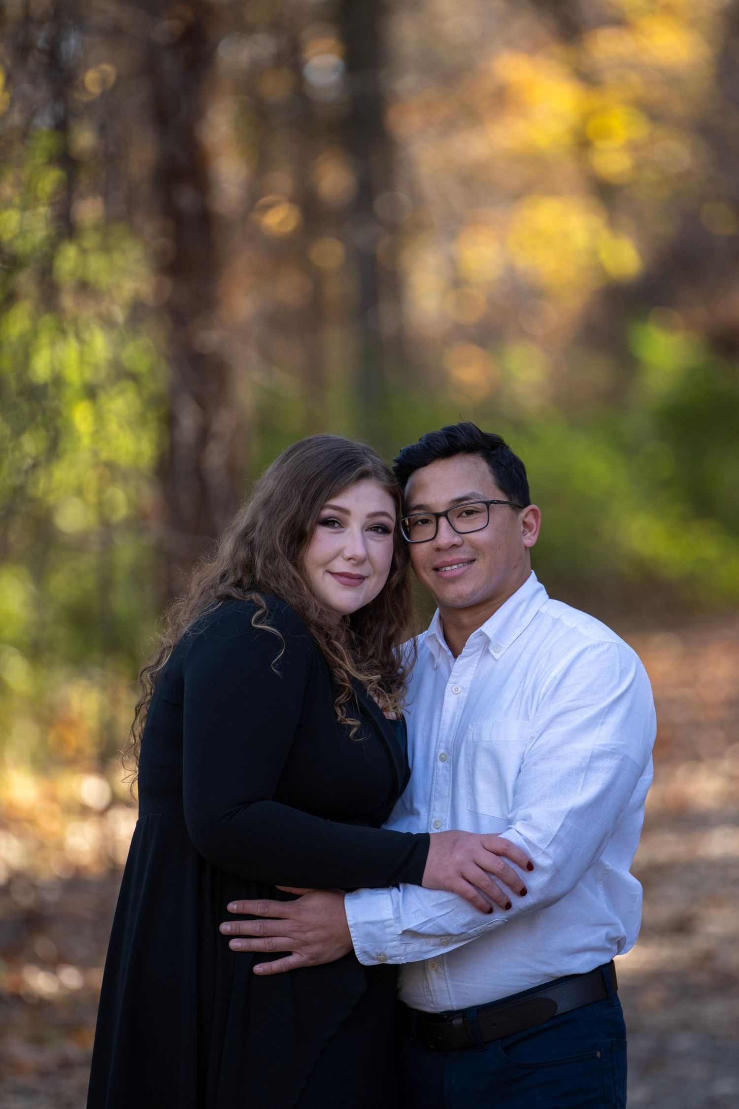 Couple shares intimate moment against blurred fall forest background.