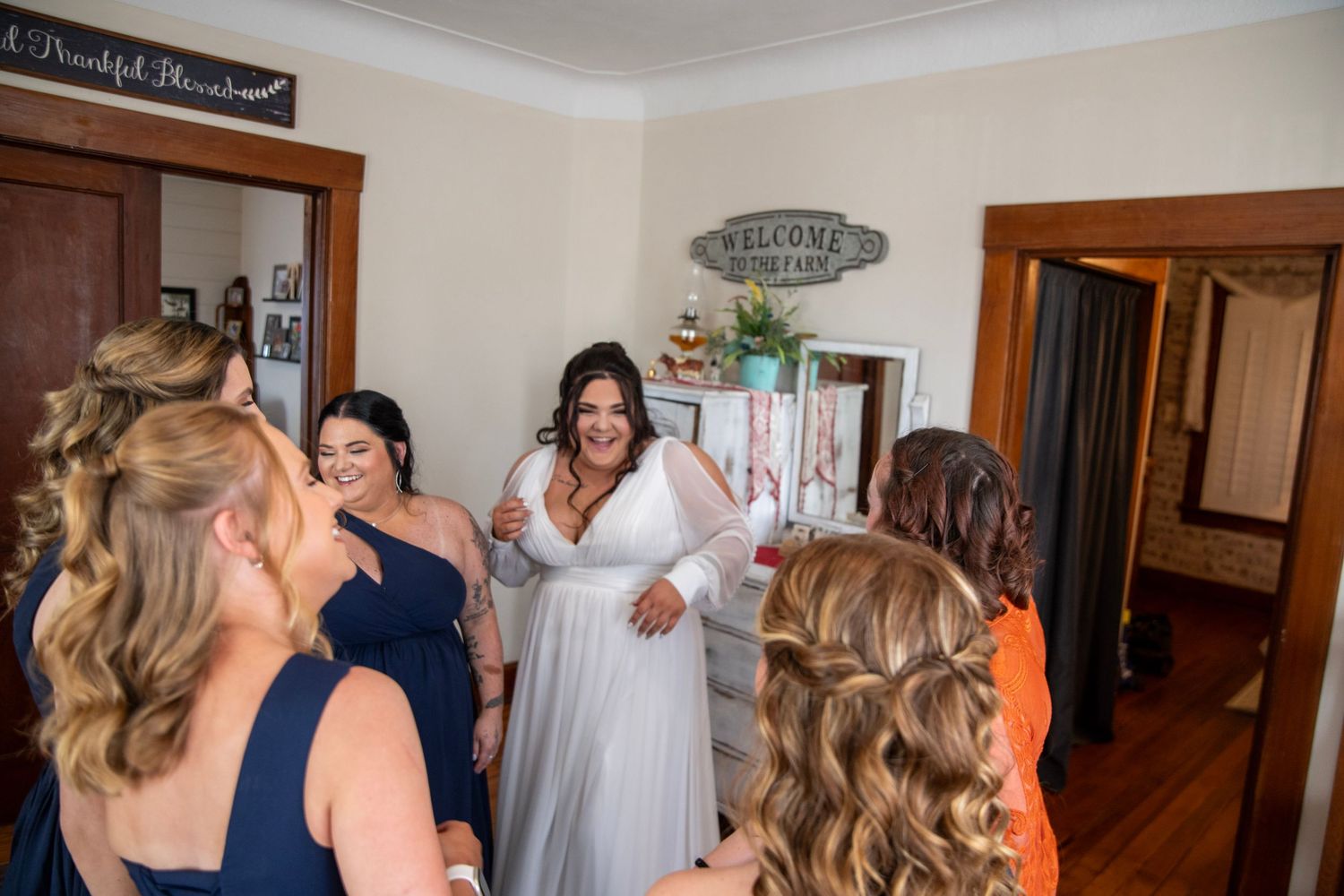 Group of bridesmaids in matching navy gowns share an emotional moment during wedding preparations.