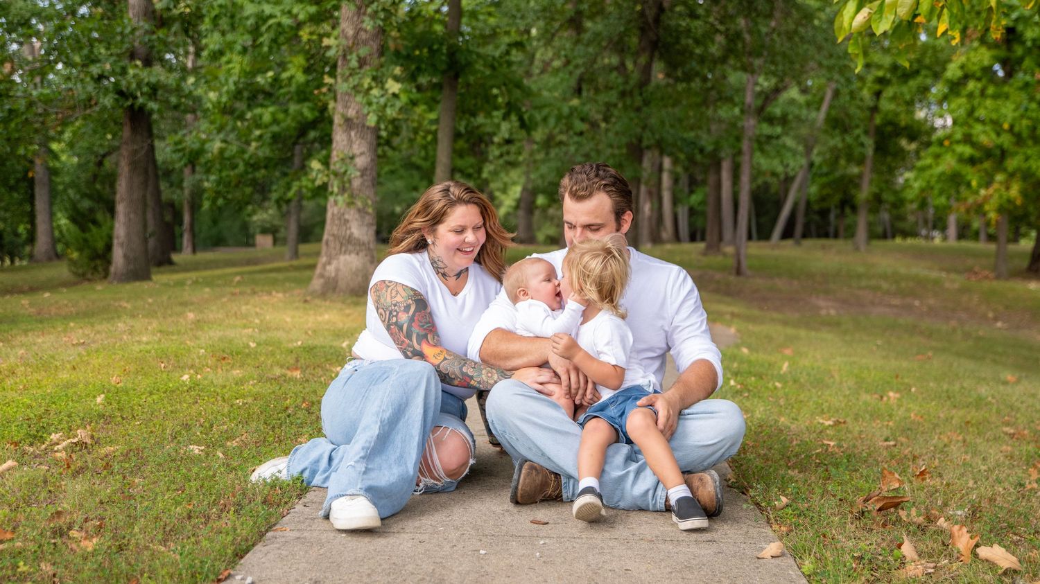 Wide angle shot of a family relaxing together on grass in a park.
