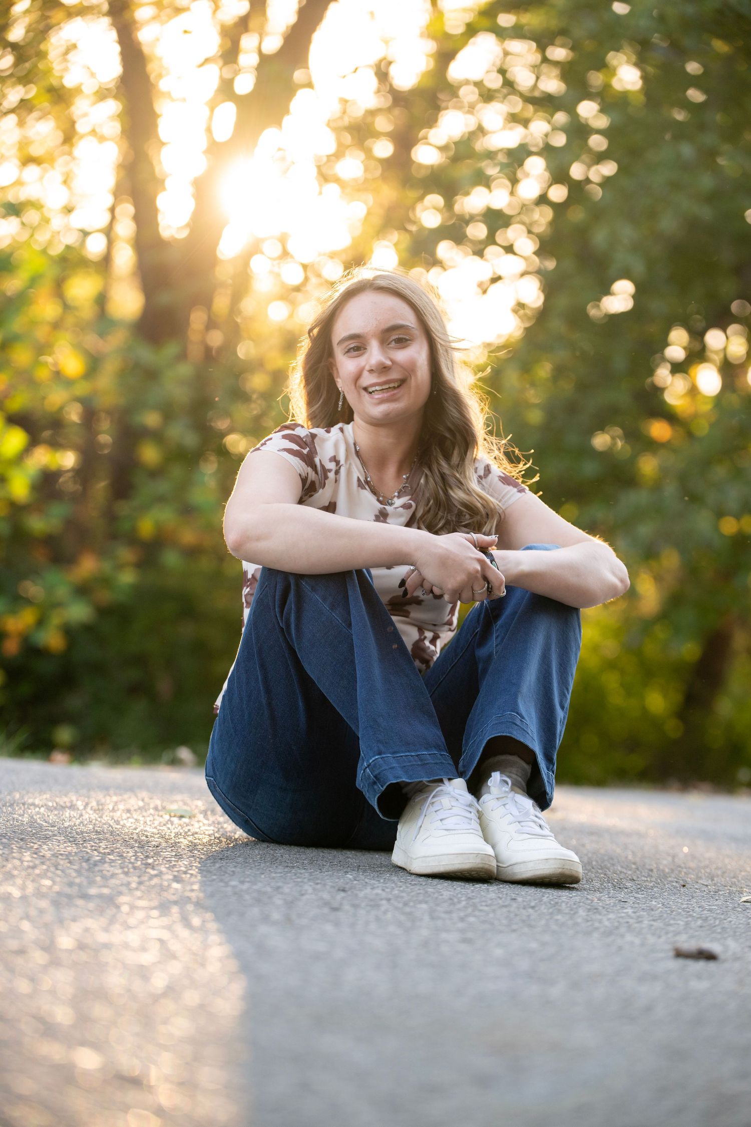 A casual outdoor photoshoot with someone sitting on pavement during golden hour.