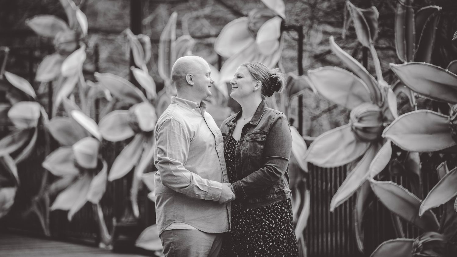 Couple sharing a romantic moment among blooming cherry blossoms in a garden setting.