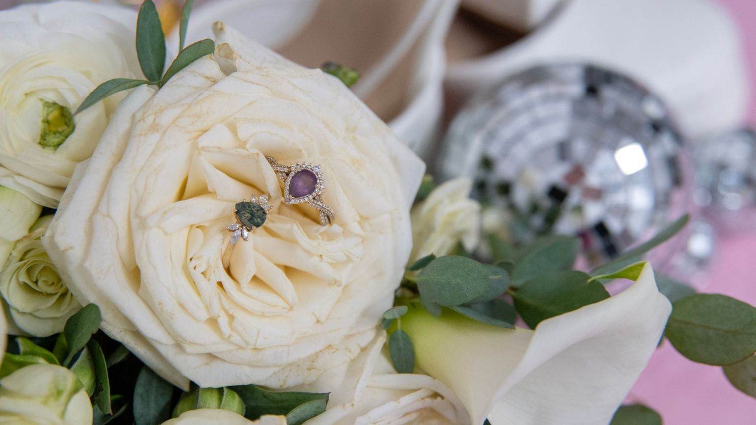 Delicate cream roses and silver disco balls arranged as wedding decor.