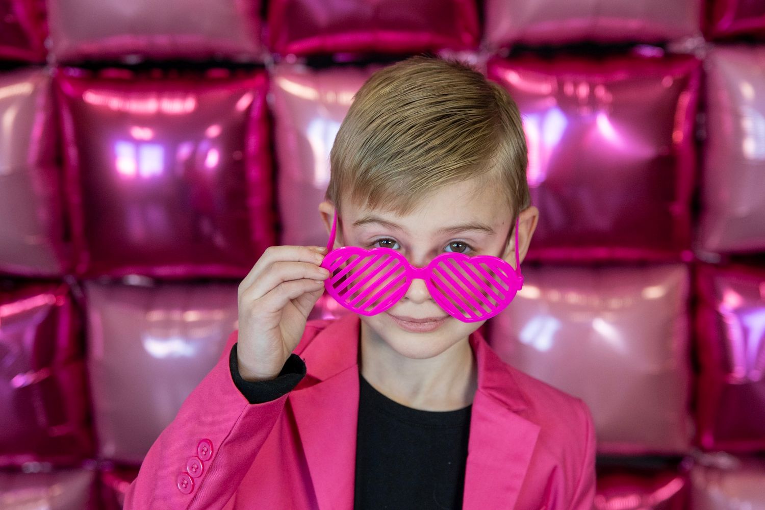 Person playfully poses with pink prop against vibrant pink theater seating.