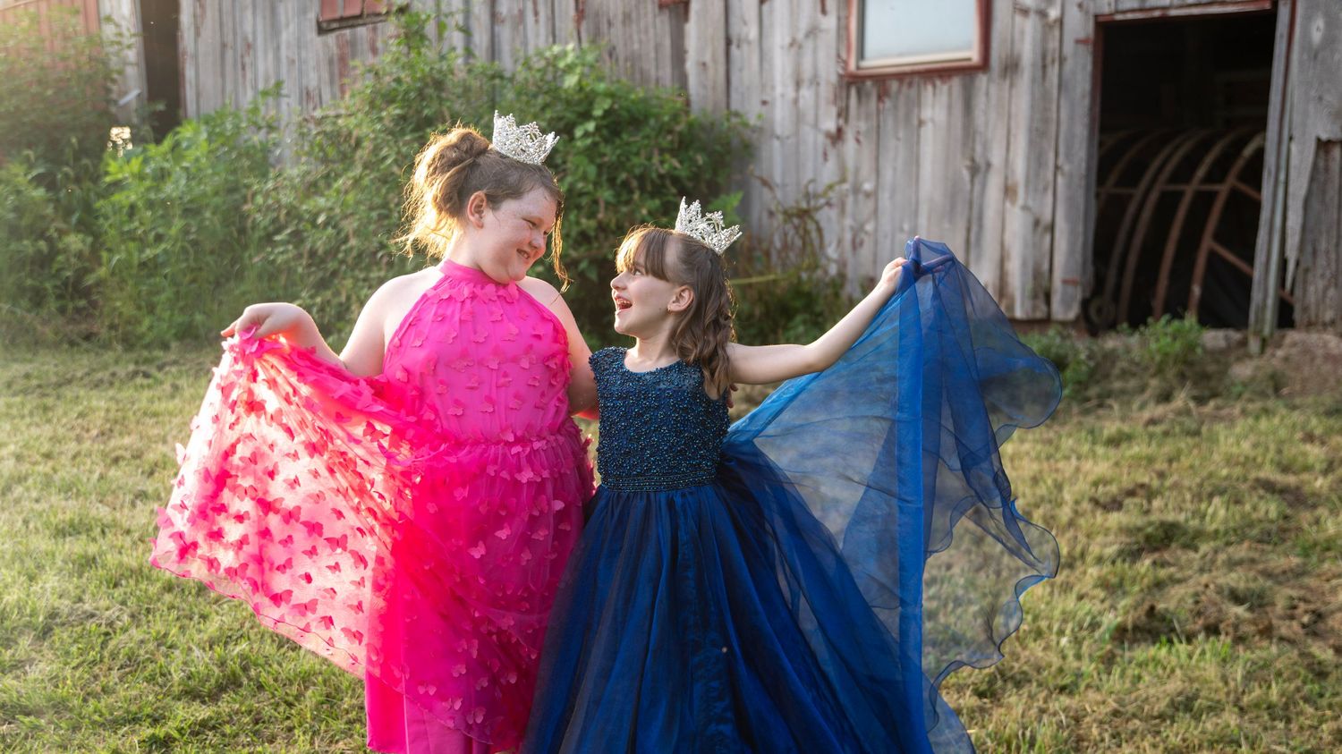 Colorful dresses flow in the breeze against a weathered barn setting.