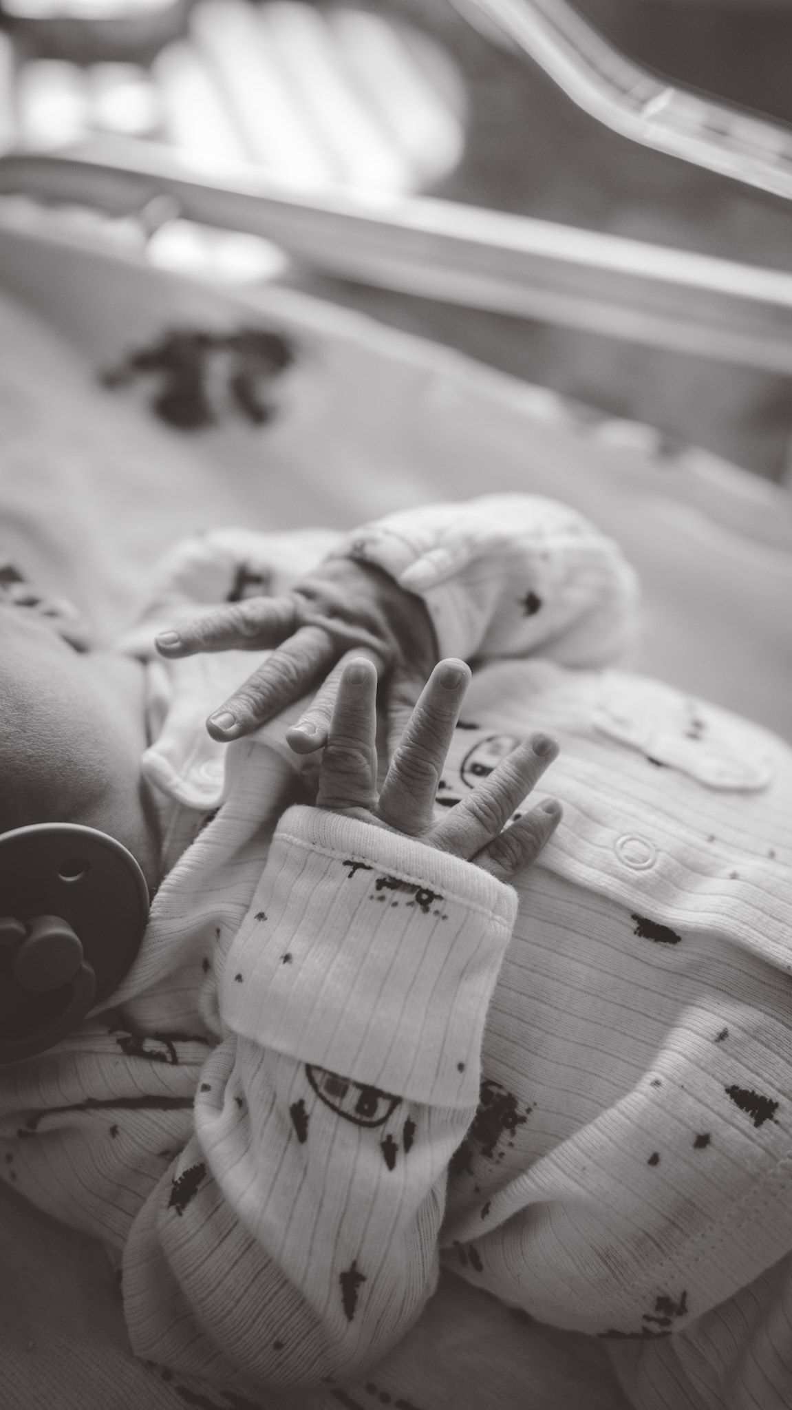 Close-up black and white photo of hands gently touching white fabric with delicate details.