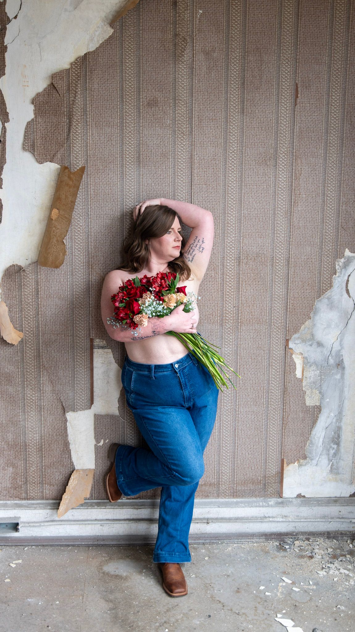 Elegant boudoir portrait with tattoo detail and red rose bouquet.