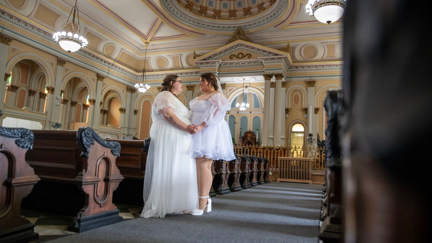 Panoramic view of an elegant ballroom with ornate architectural details and arched windows.