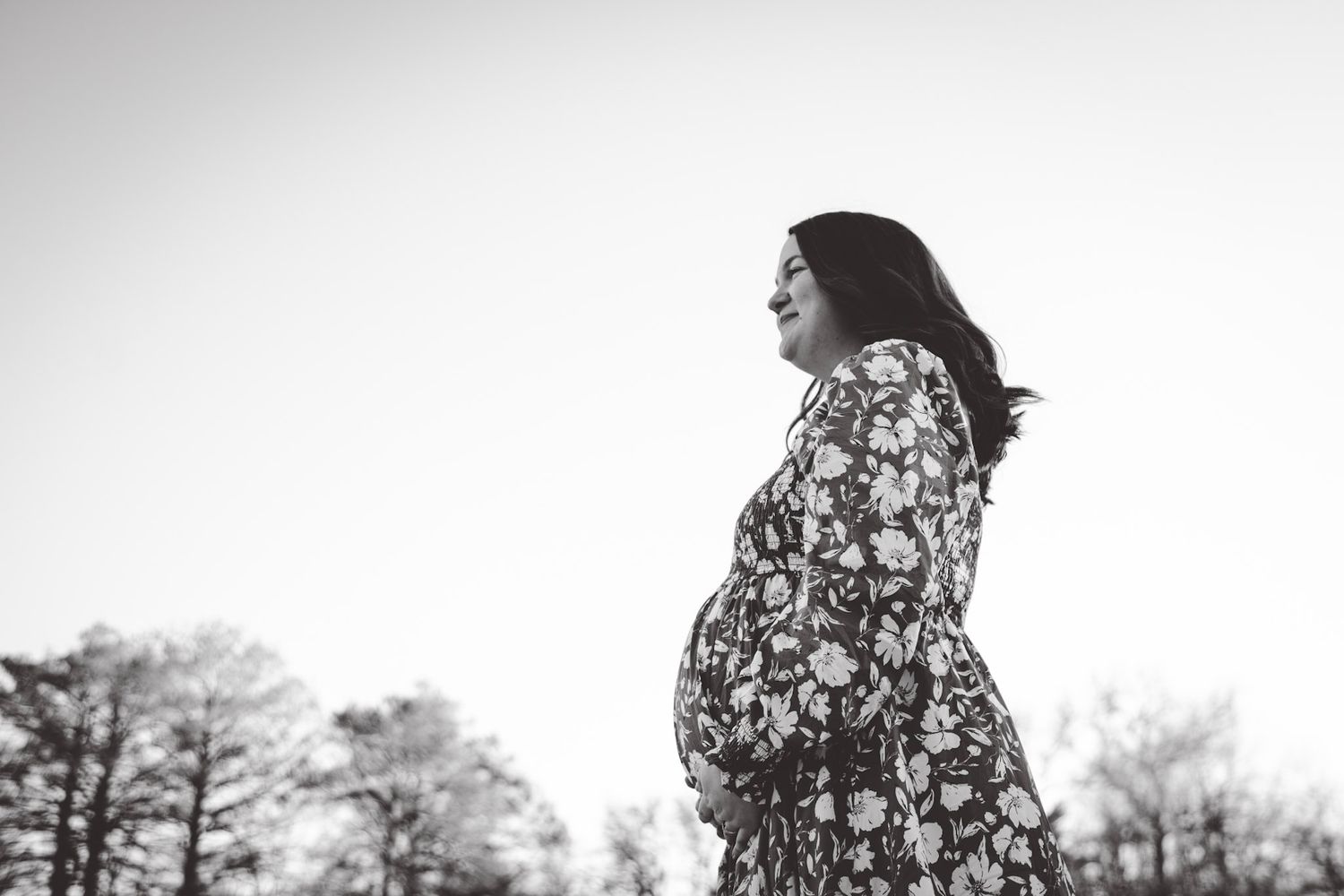 Person in floral dress twirls during outdoor sunset photoshoot.