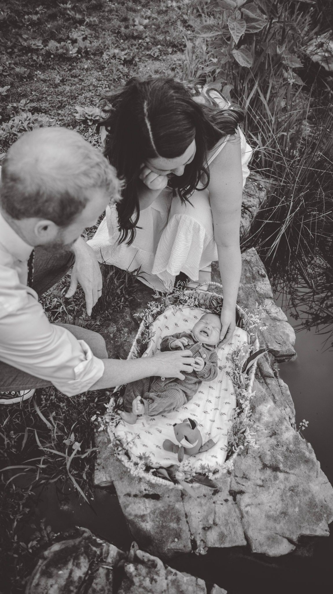 A black and white image of people examining something on the ground together.
